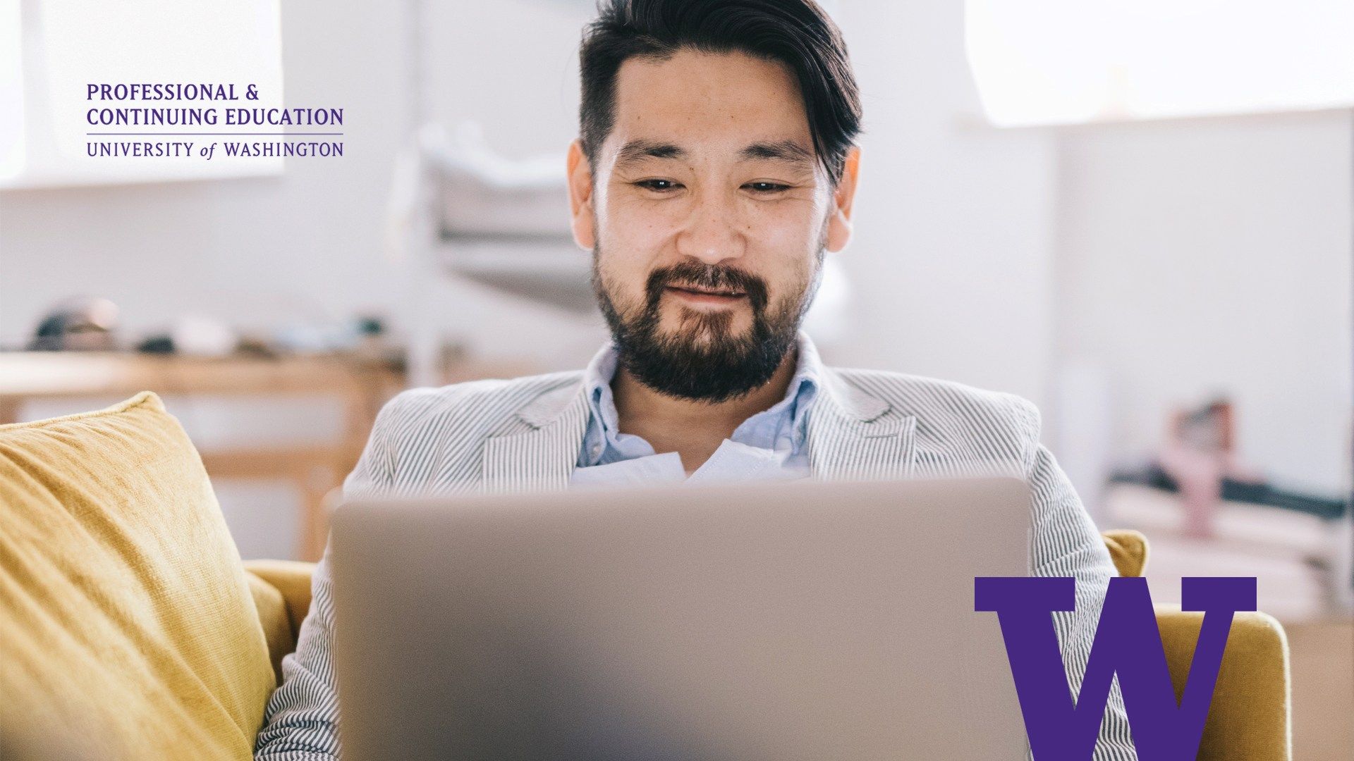 A man smiles while working on a laptop, promoting University of Washington Professional & Continuing Education.