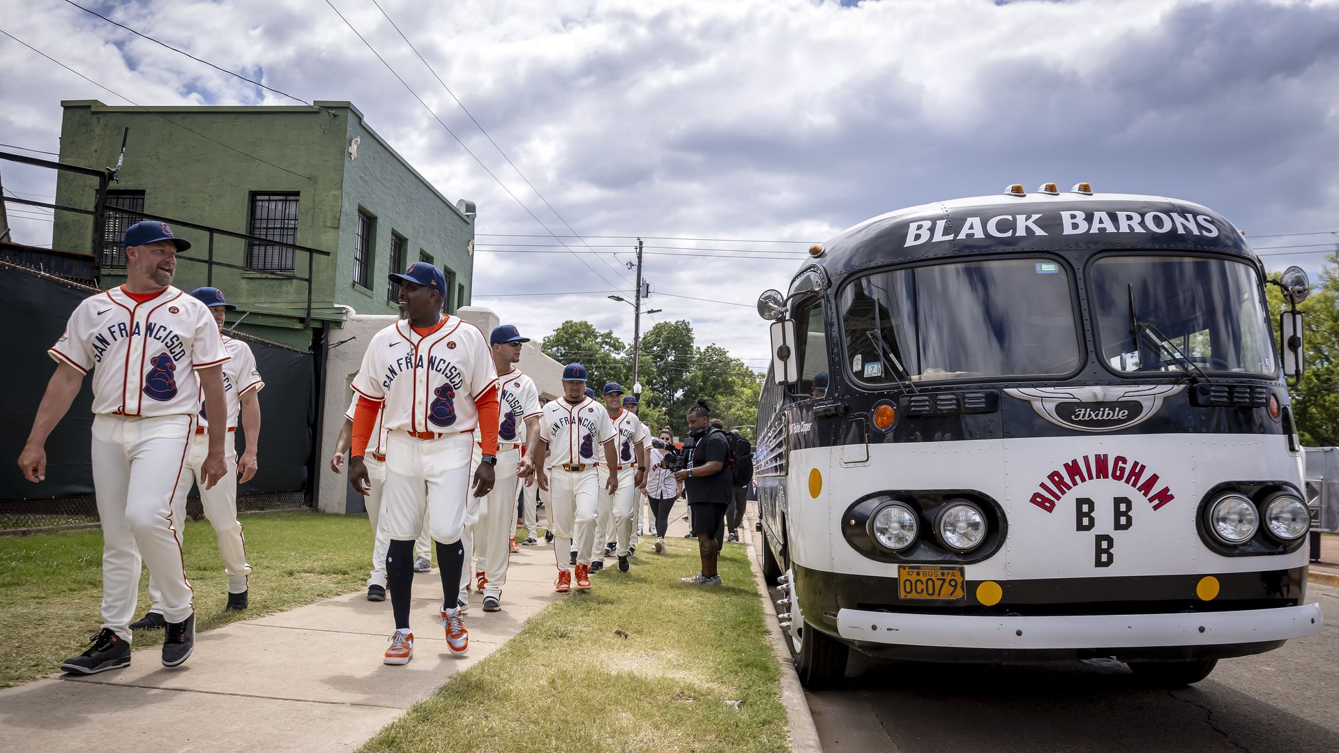 baseball players in uniforms walking next to a bus that says "black barons"