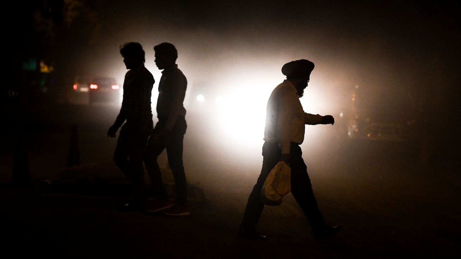 Indian commuters walk amid air pollution in New Delhi. 