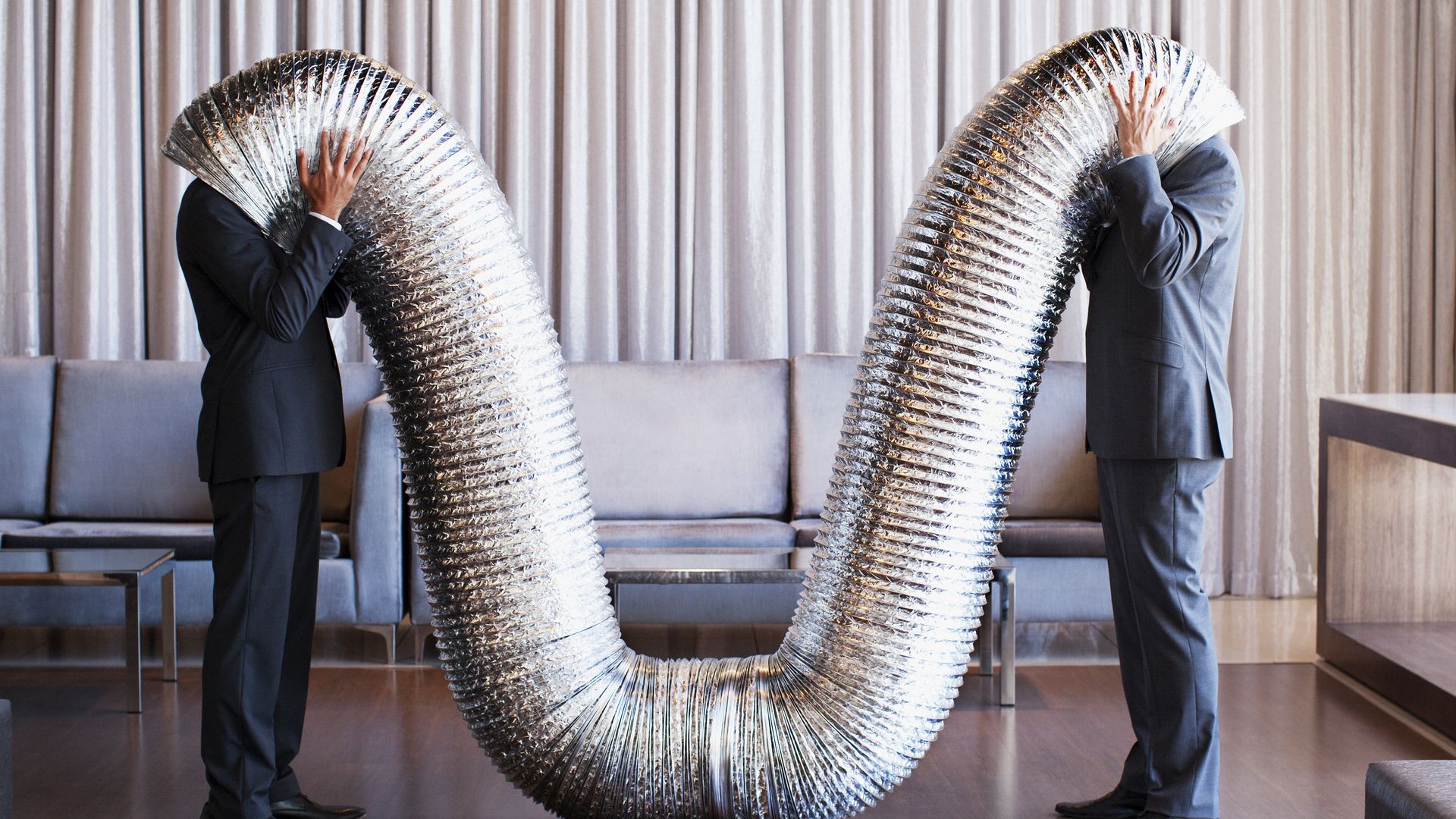 Businessmen with their heads inside metal tubing
