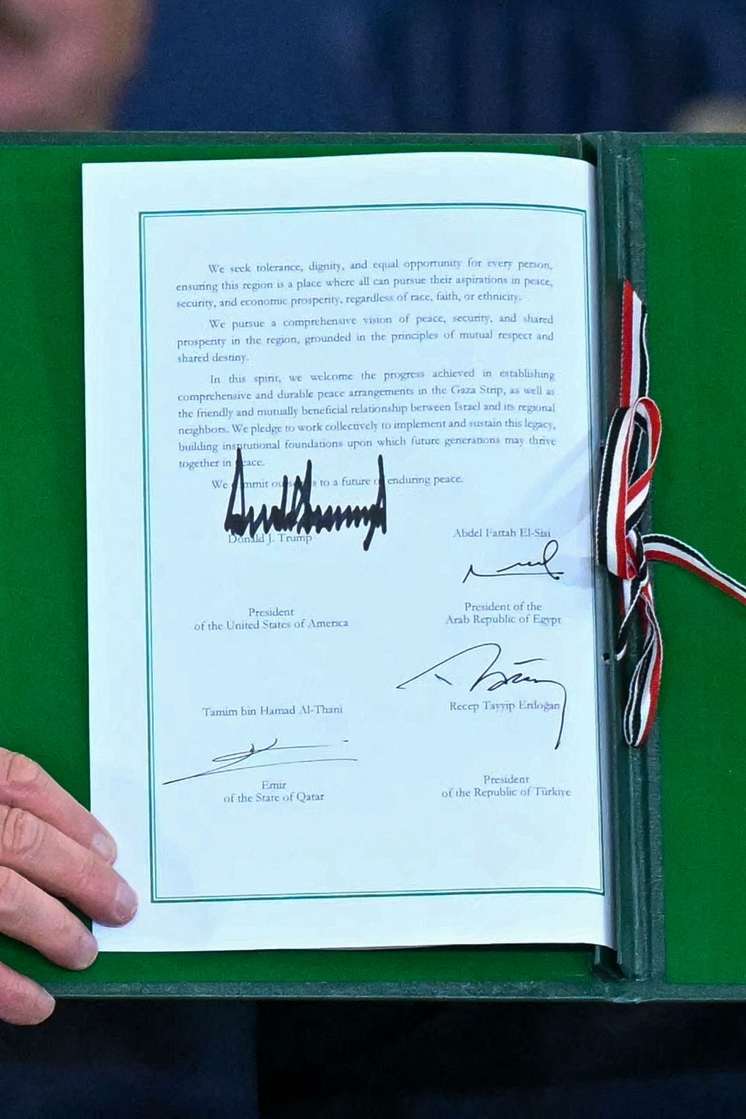 US President Donald Trump shows a signed document during a summit on Gaza in Sharm el-Sheikh on October 13, 2025. Trump landed in Egypt on October 13 for a summit on Gaza, following a lightning visit to Israel after a ceasefire he brokered entered into force. (Photo by SAUL LOEB / AFP) (Photo by SAU