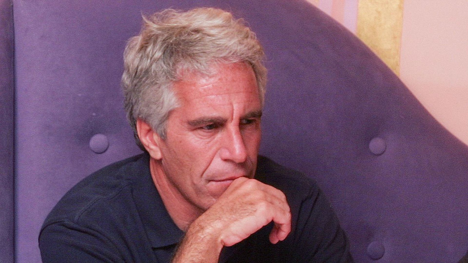 Jeffrey Epstein sits, posing for a photo.