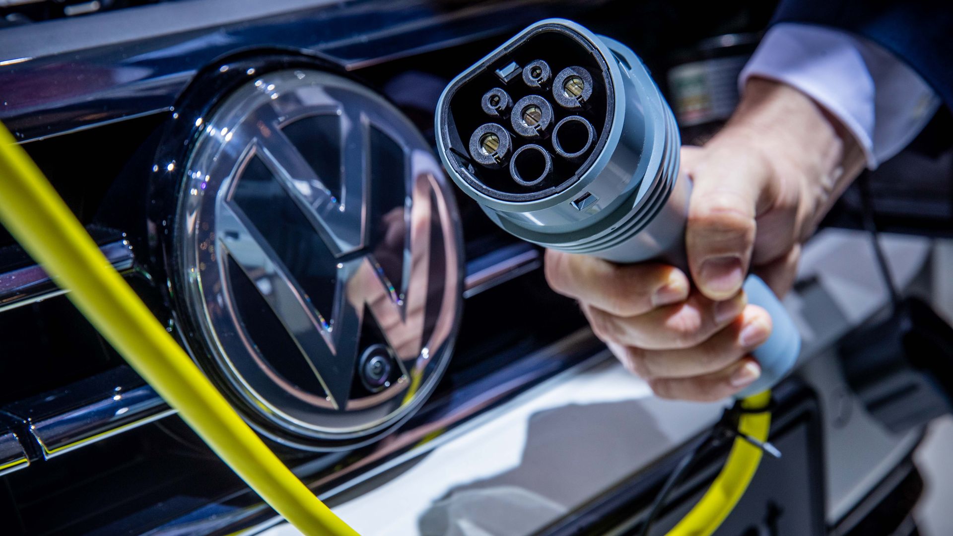 Image of someone about to plug an electric charger cord into a VW car