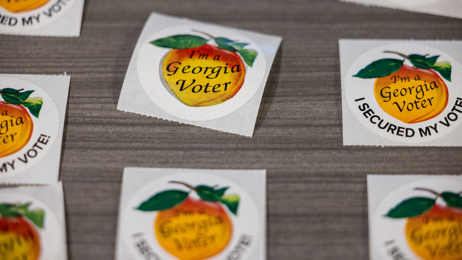 Several stickers that read "I'm a Georgia voter" and "I secured my vote!" are lined up in three rows on a gray surface.