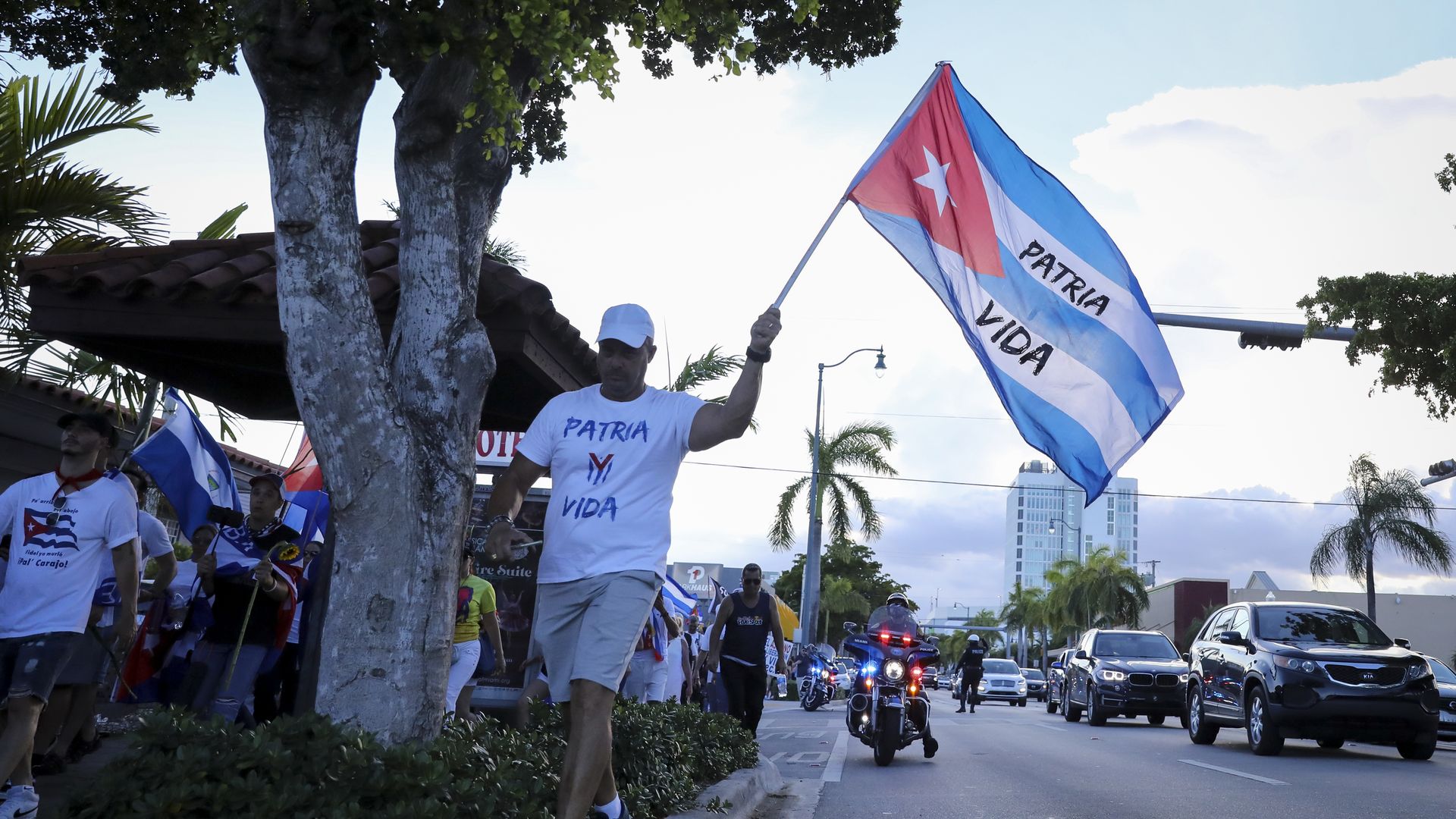 A man waves a Cuban flag against the sky. 