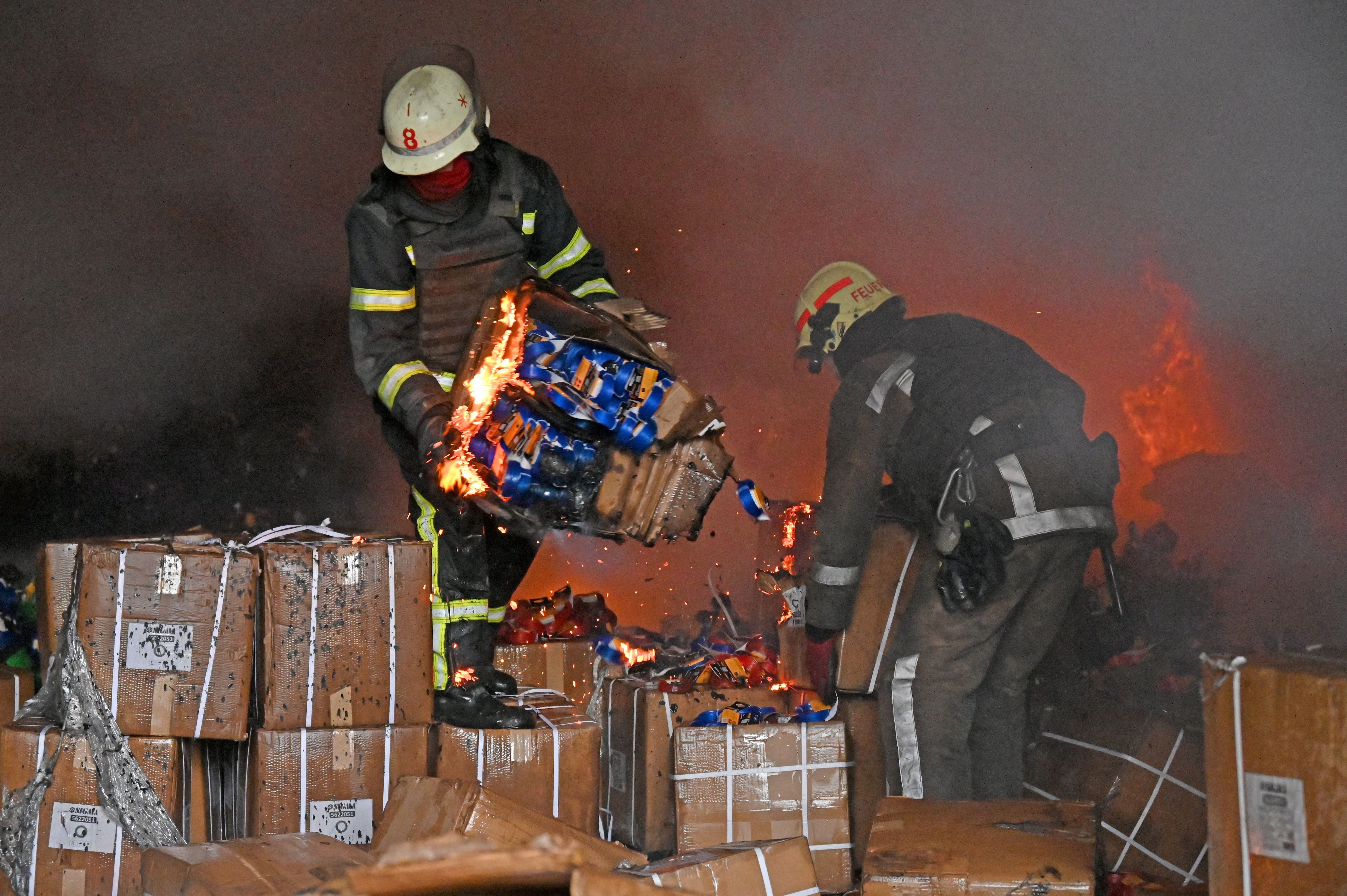 Firefighters hold boxes as they try to extinguish a fire after a missile hit a warehouse on the outskirts of Kharkiv on April 1.
