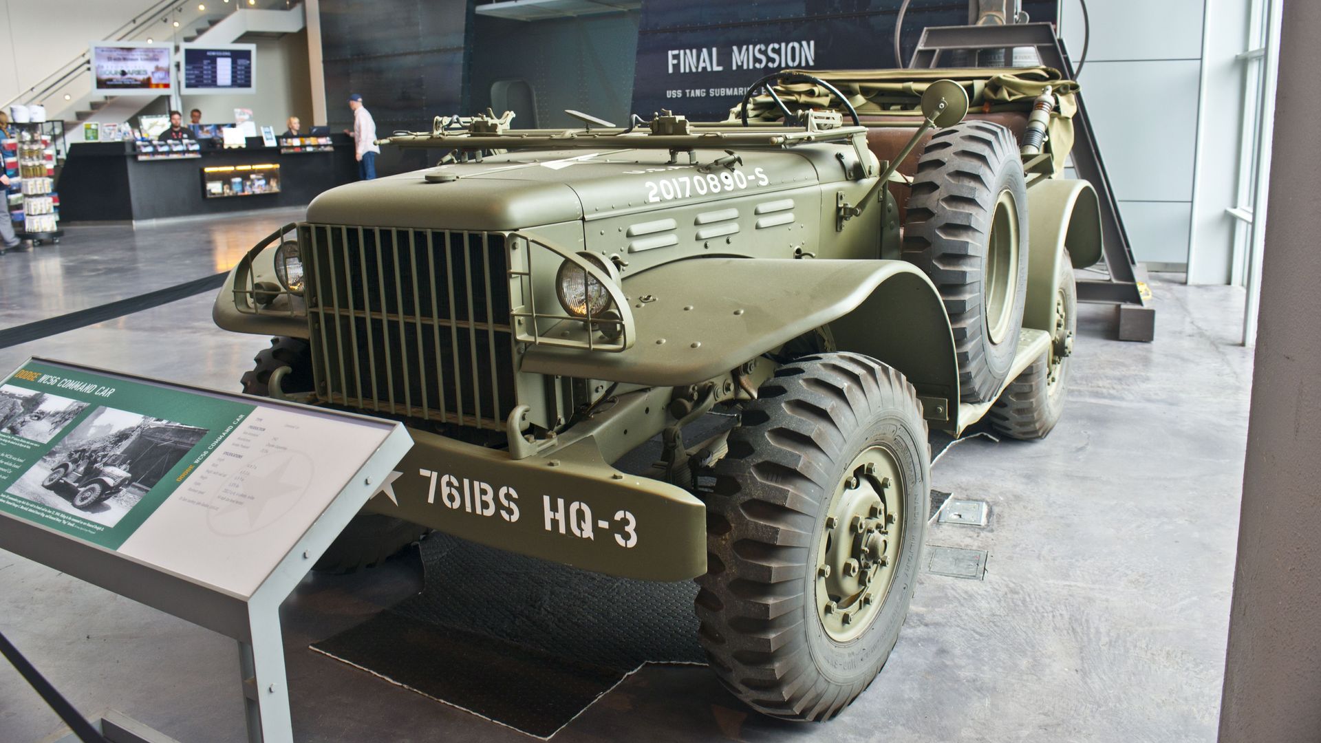 A vintage-looking, army-green vehicle is parked inside a museum exhibition.