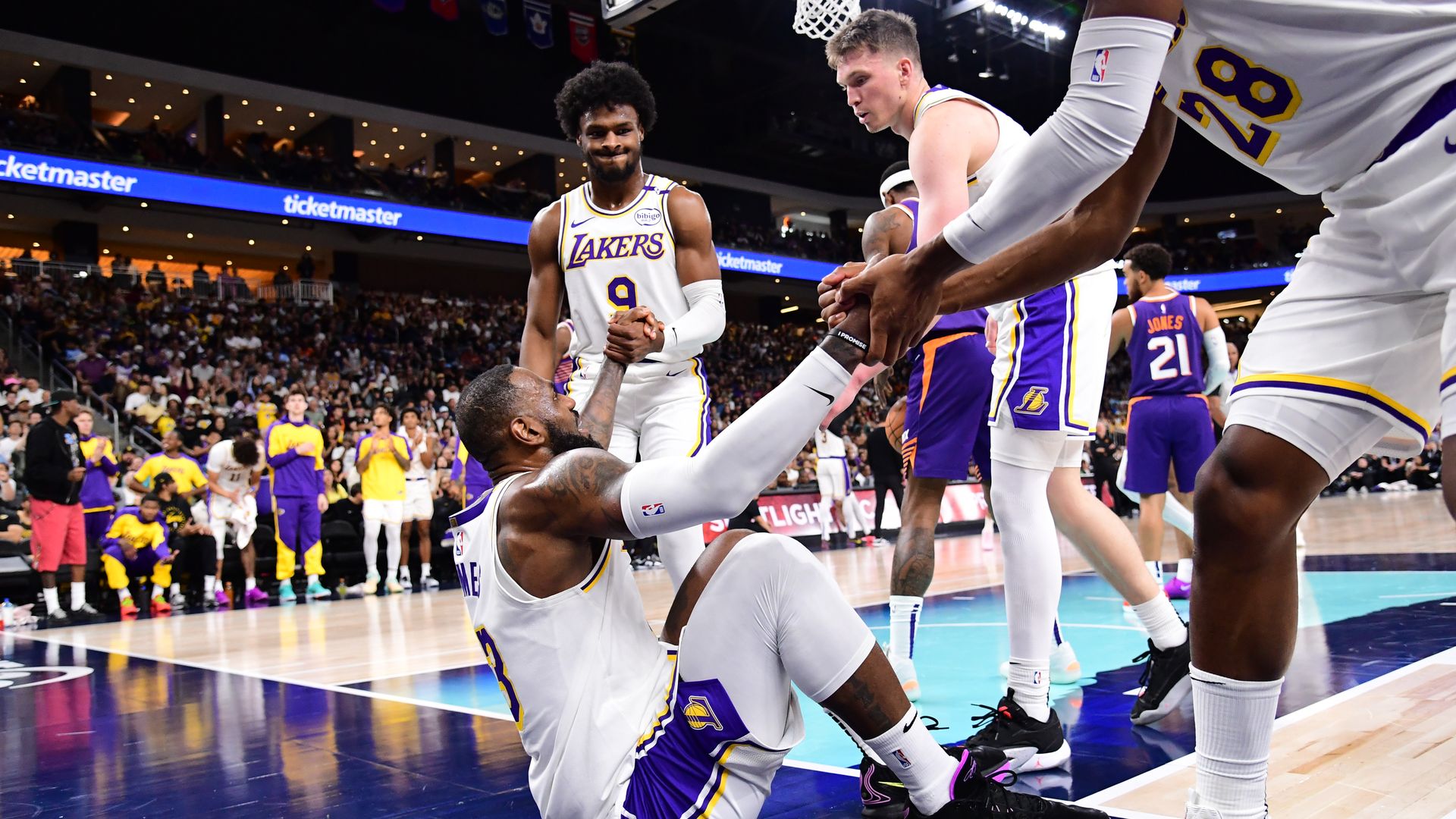 LeBron James #23 helped up by Bronny James #9 and Rui Hachimura #28 of the Los Angeles Lakers during the game against the Phoenix Suns on October 6, 2024 at Acrisure Arena in Palm Springs, California.