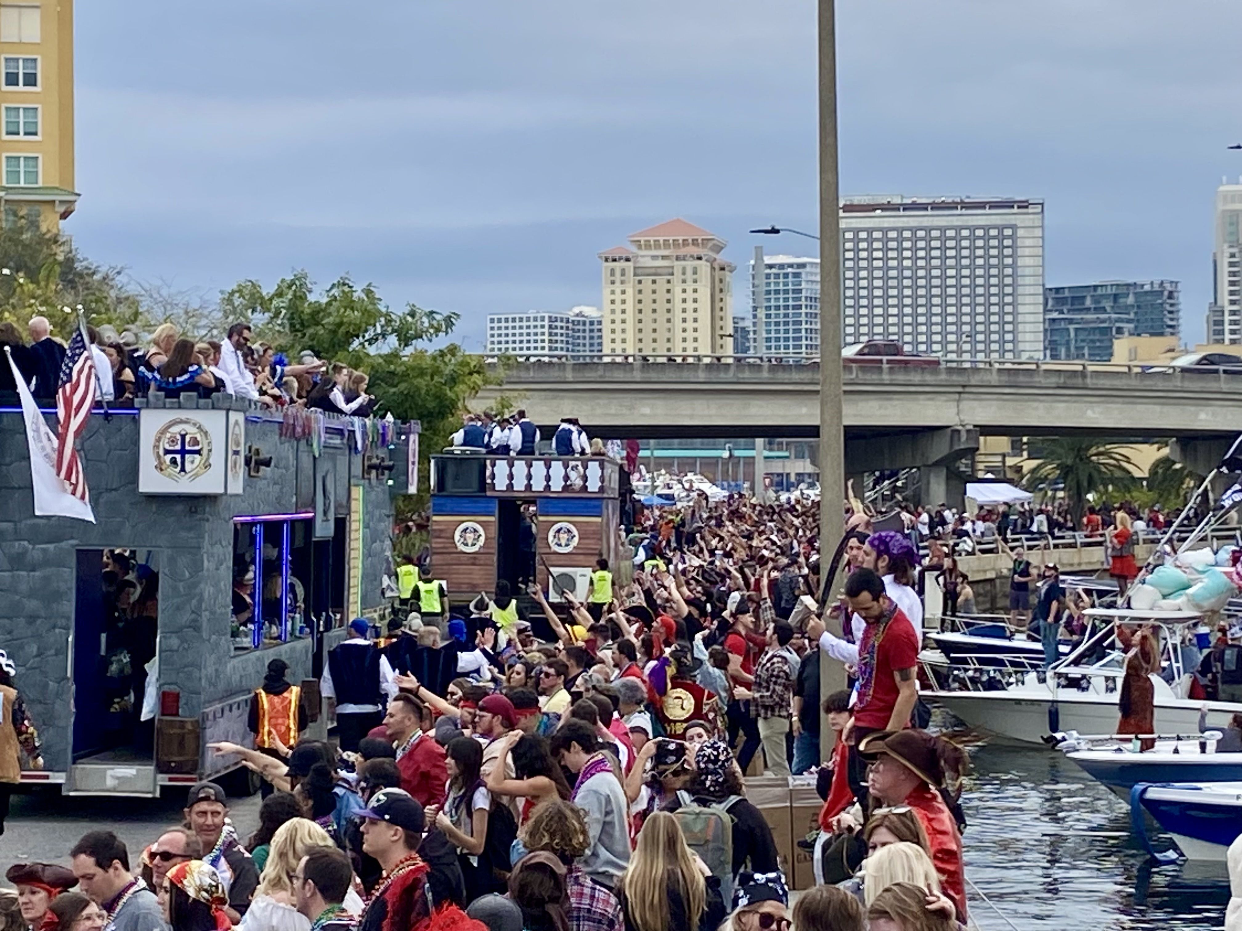 People at the Gasparilla fest reach for beads.