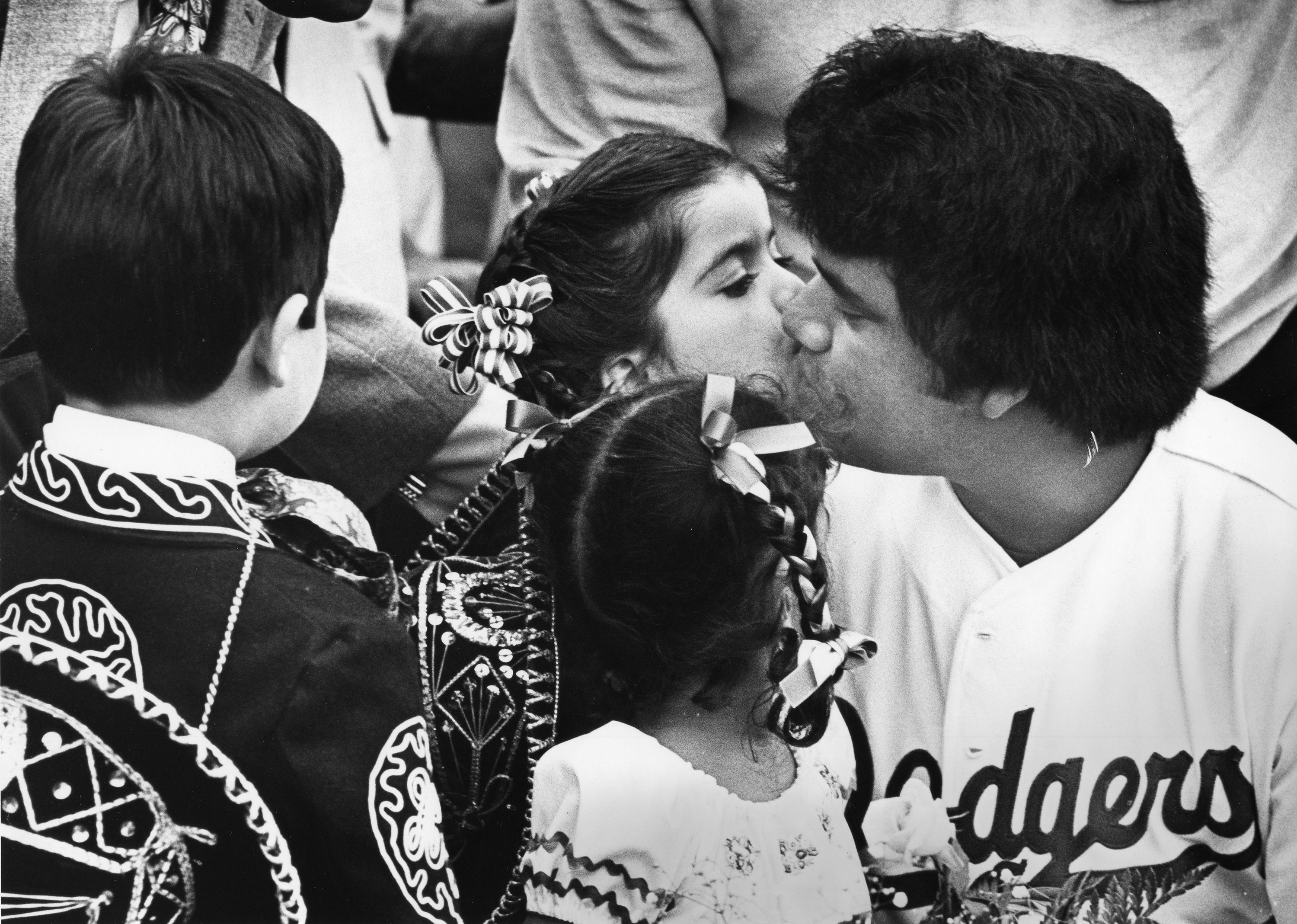 a young girl gives a kiss to Fernando Valenzuela, who is in his Dodgers uniform.