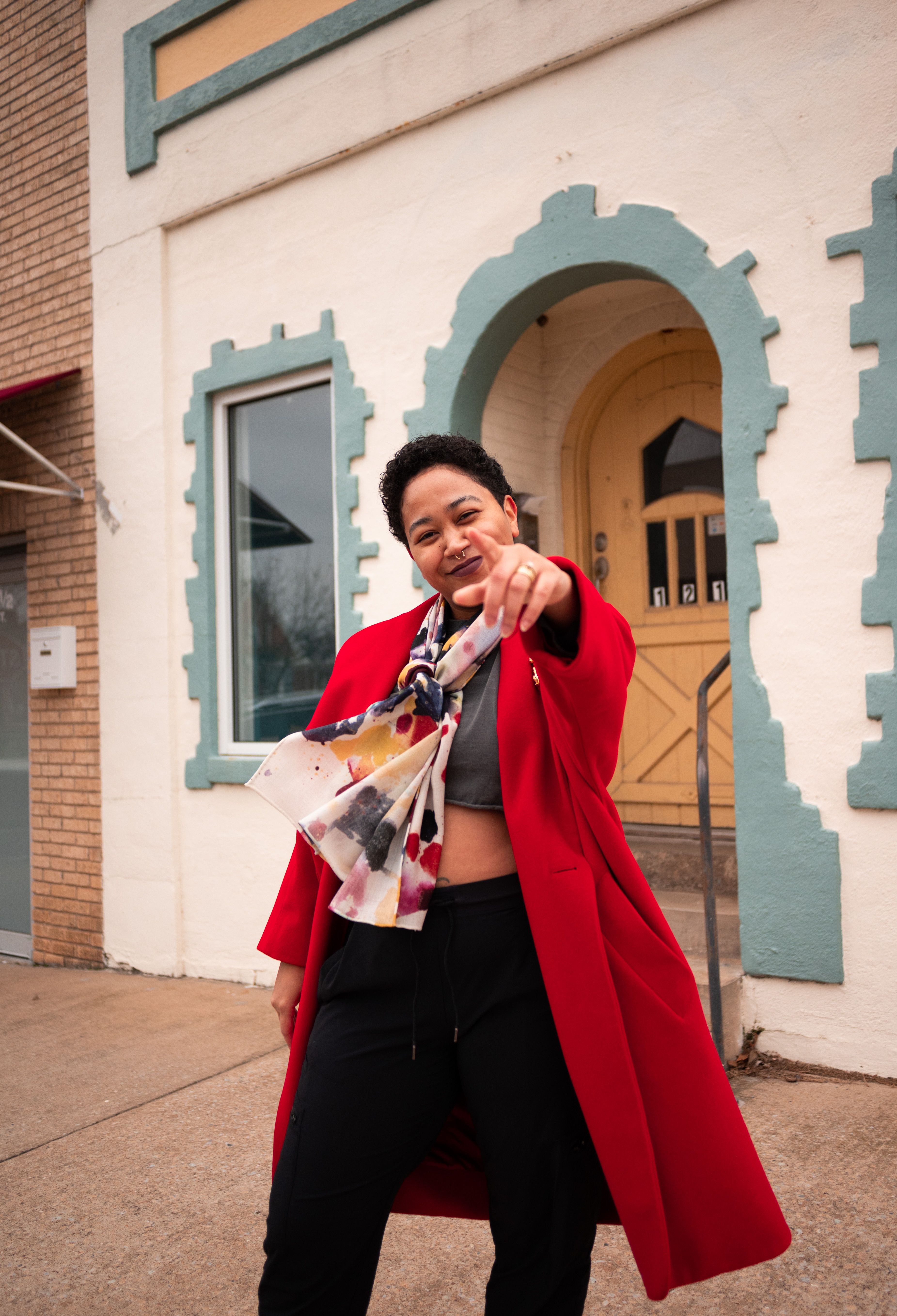 Anela Malik, an online influencer and author, stands on a street, pointing at the camera. 