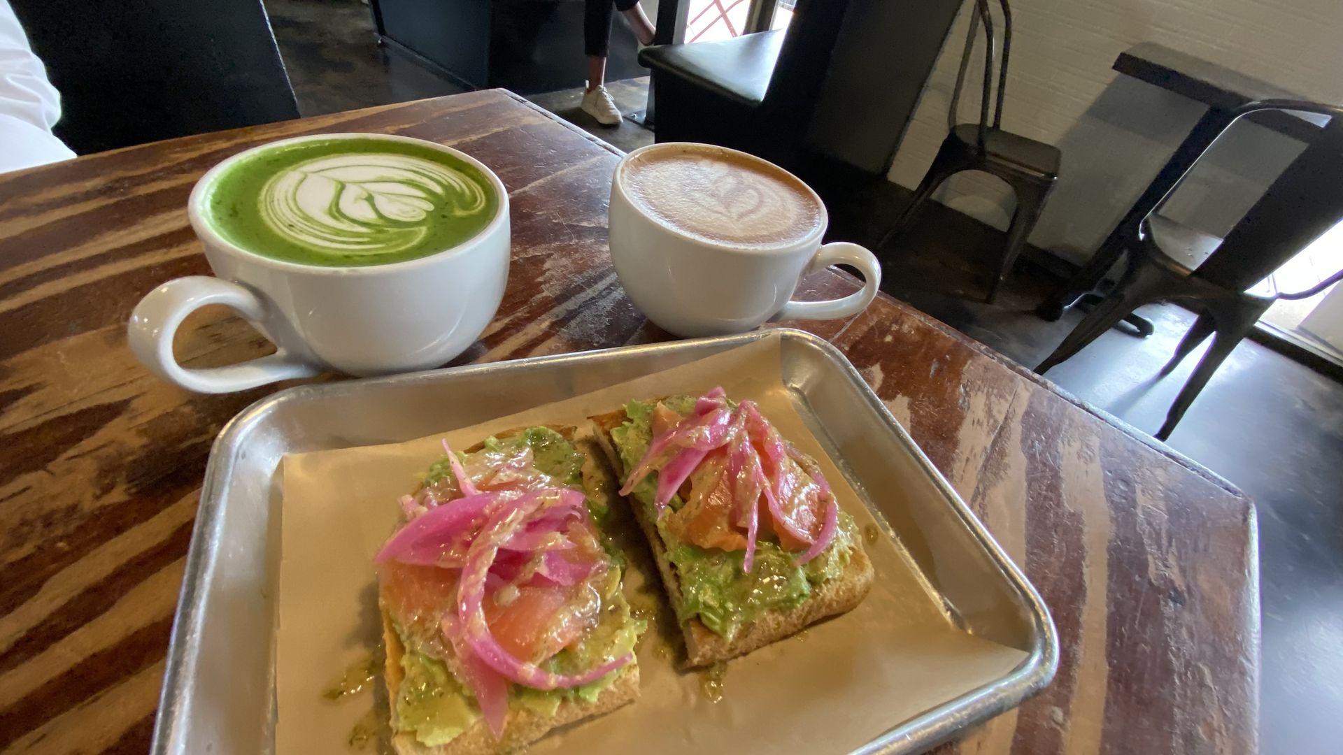 A photo of two cups of coffee and toast on a table.