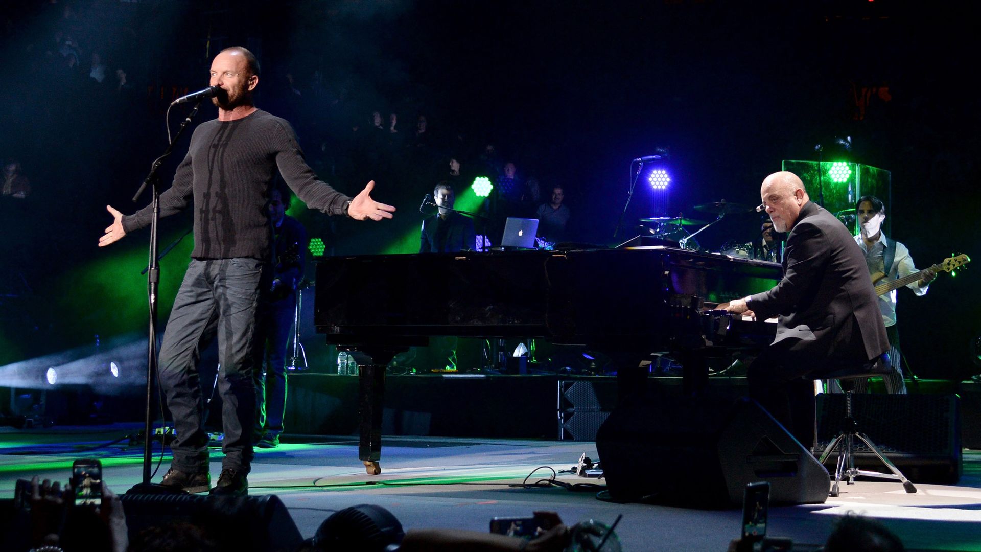 Billy Joel and Sting performing on a stage. 