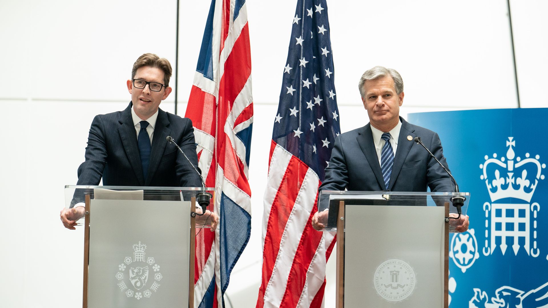 Photo of Ken McCallum and Chris Wray standing at podiums next to each other