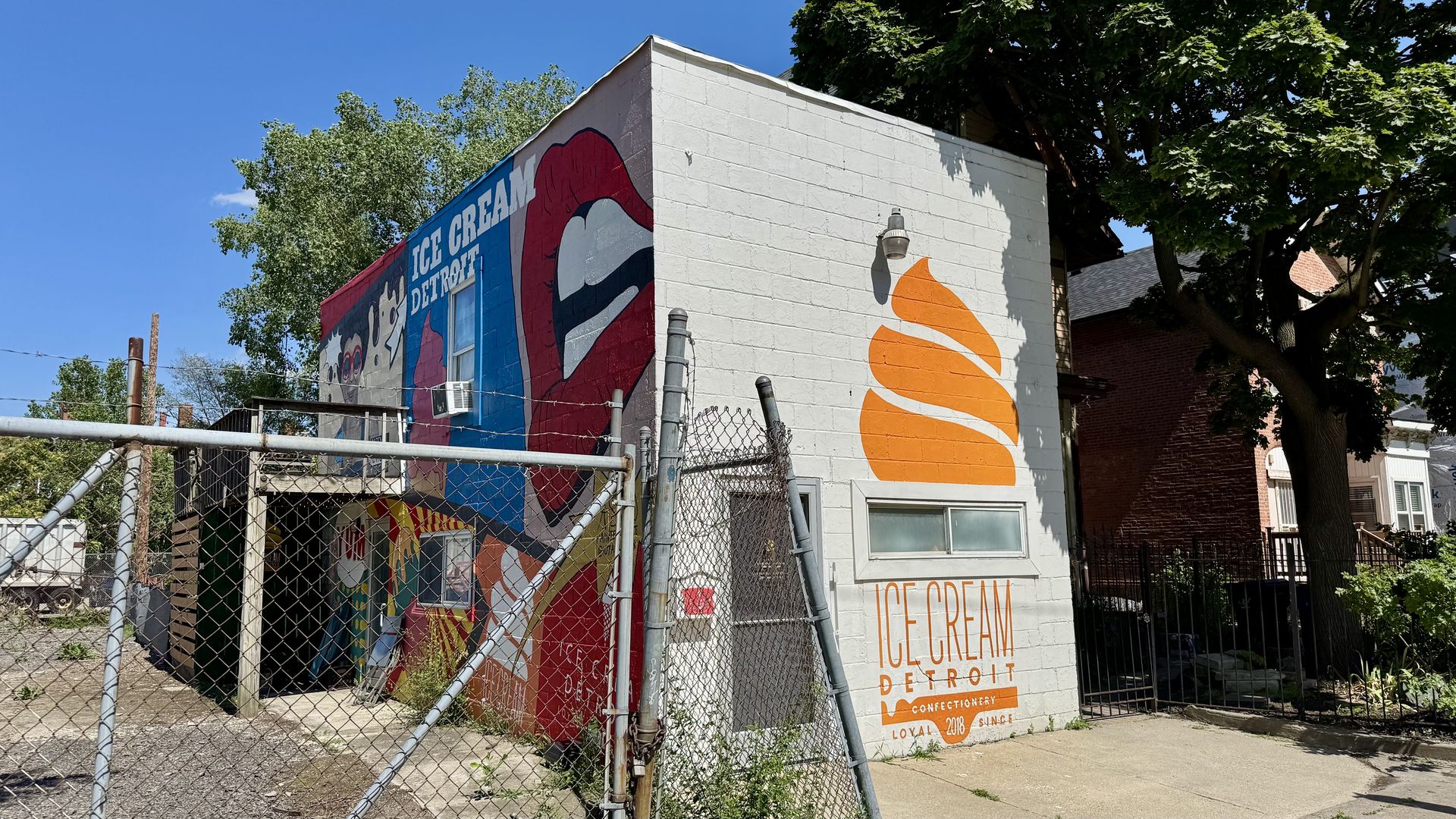 A building is shown with a bright orange ice cream logo and a colorful mural on the side