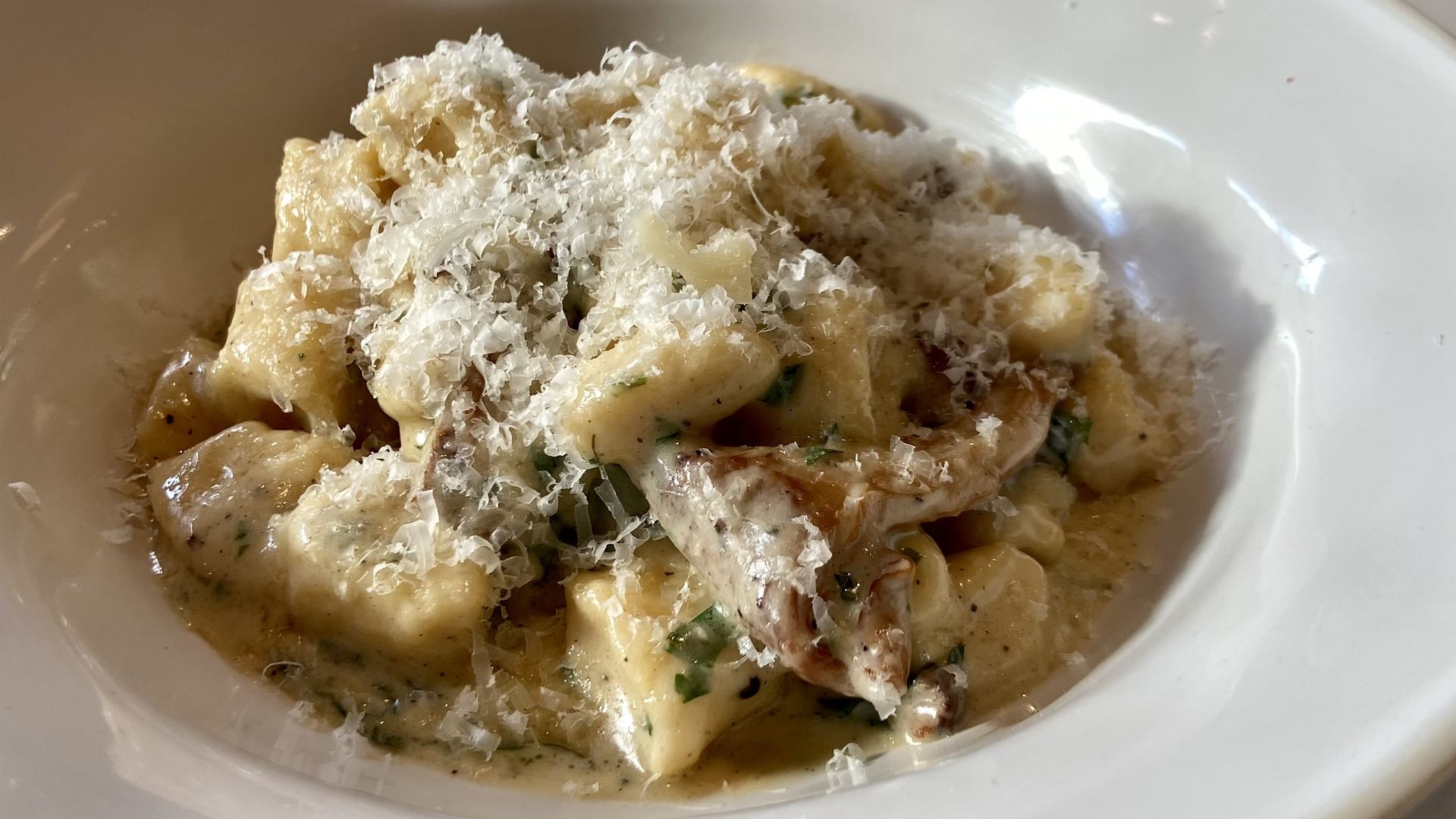 Photo shows cooked gnocchi and mushrooms covered in sauce and cheese