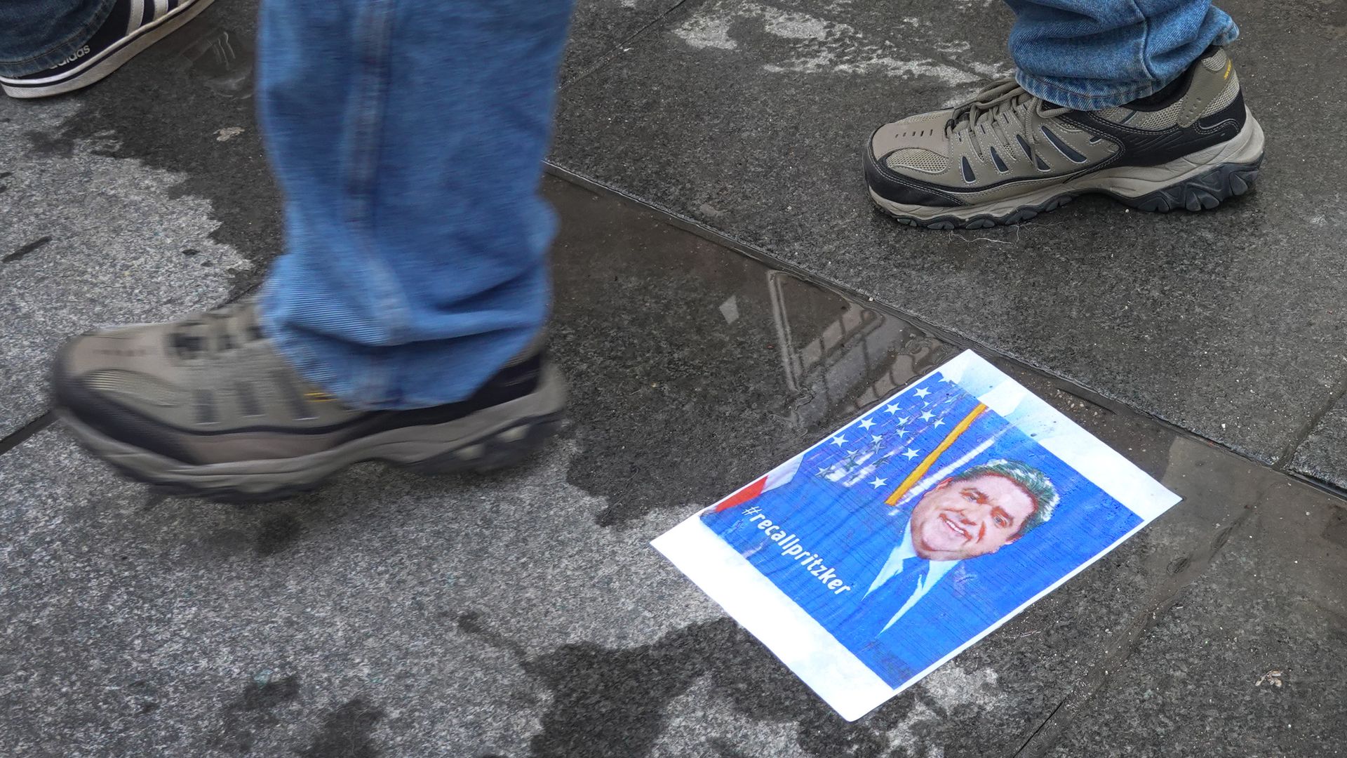 A photo of Illinois Gov. J. B. Pritzker on the ground as protesters gather against his stay-at-home orders
