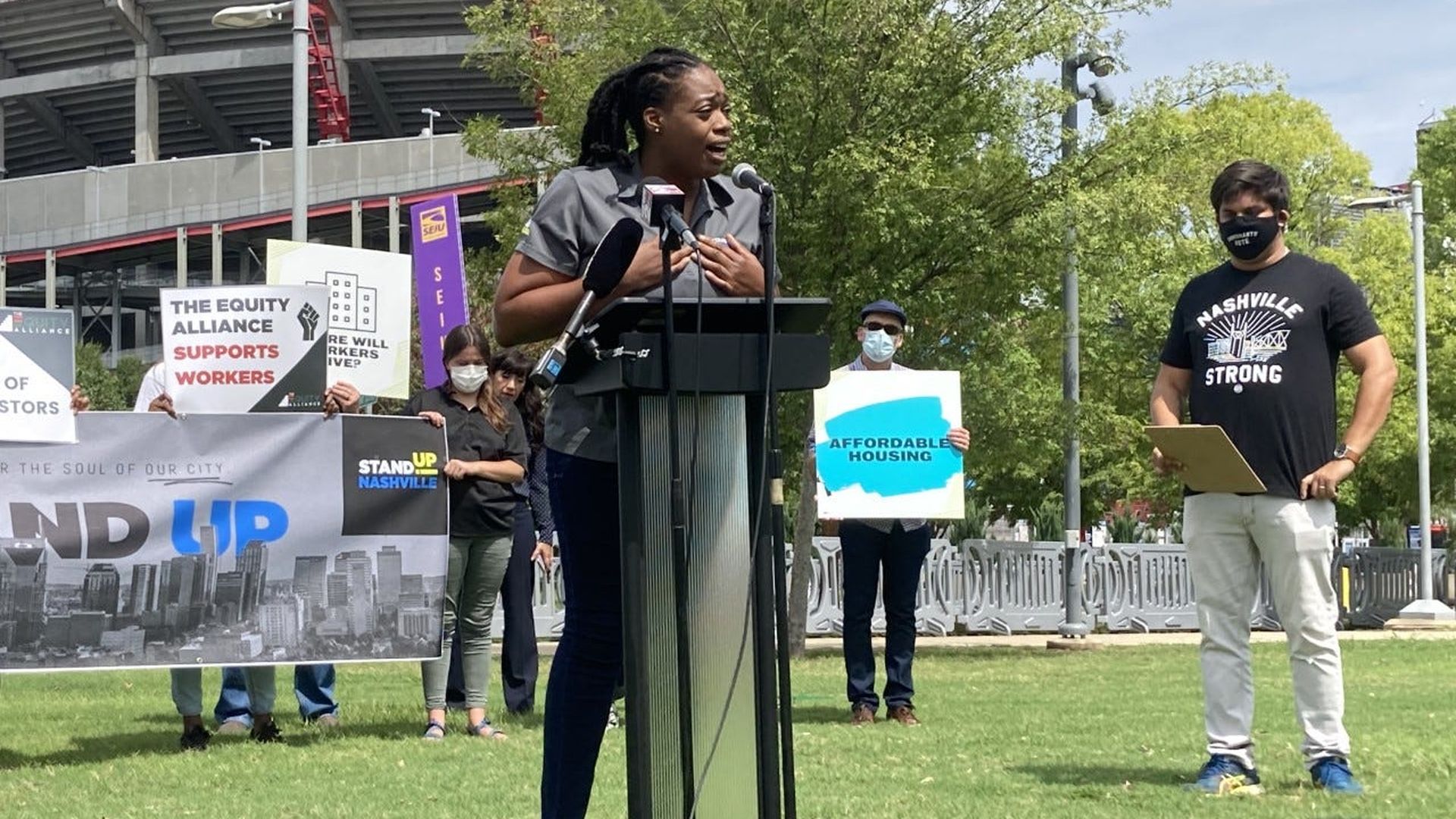 Odessa Kelly speaking at a podium on a grassy lawn