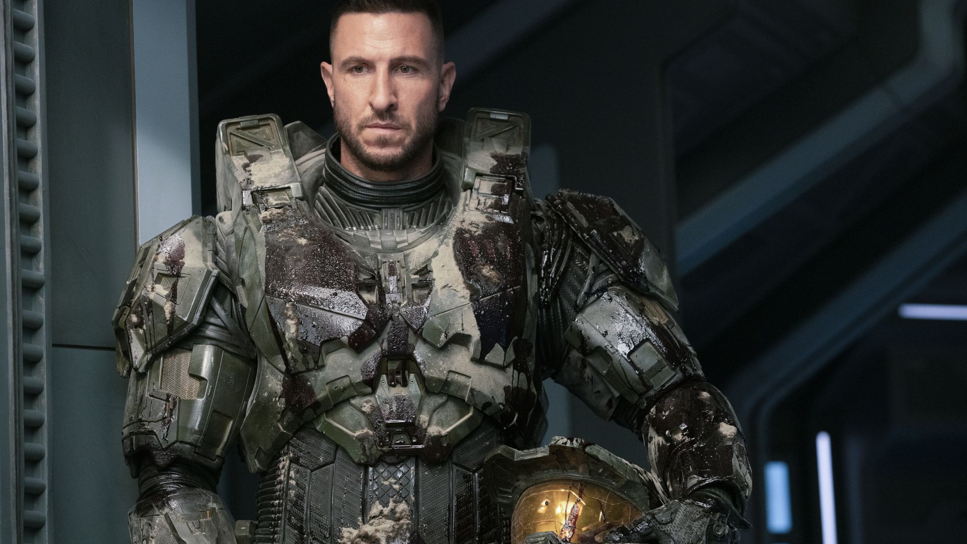 Photo of an actor wearing sci-fi space marine armor, holding a helmet with a gold visor