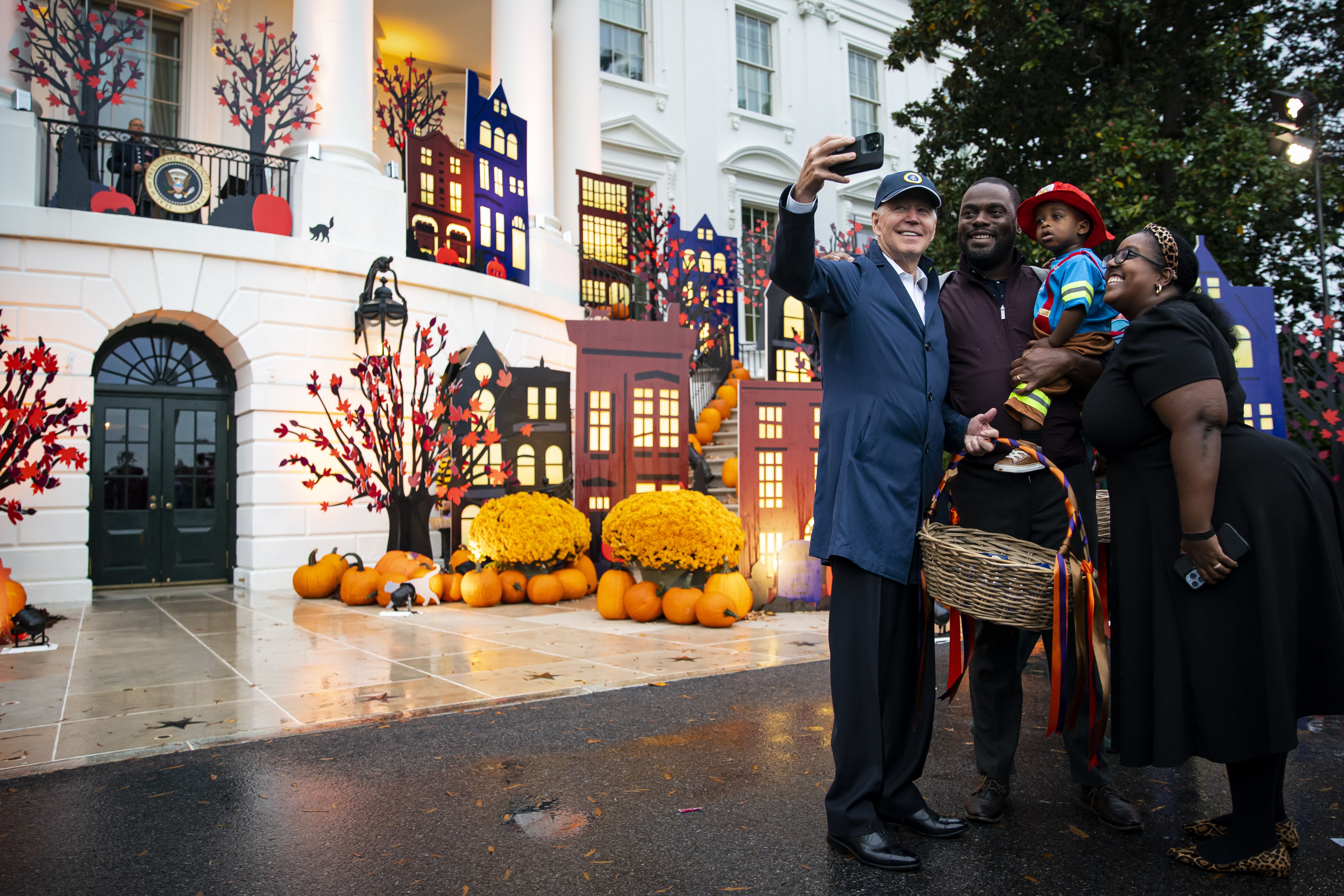 Joe Biden takes a selfie photograph with children dressed up in costumes during a Halloween event