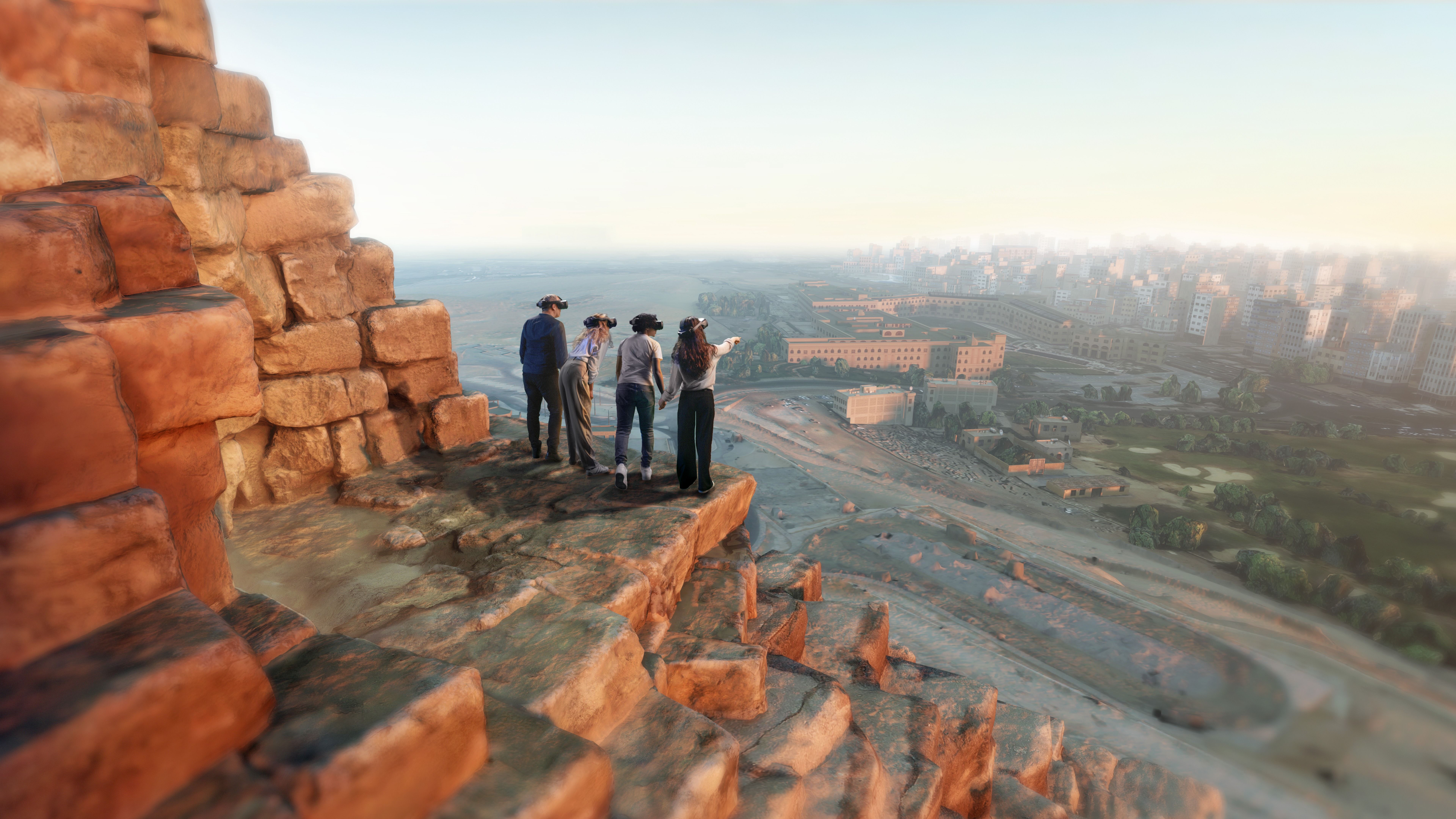 Five people wearing VR headsets stand on a rocky cliff edge, looking over a hazy cityscape of buildings and roads, with orange rocks in the foreground.