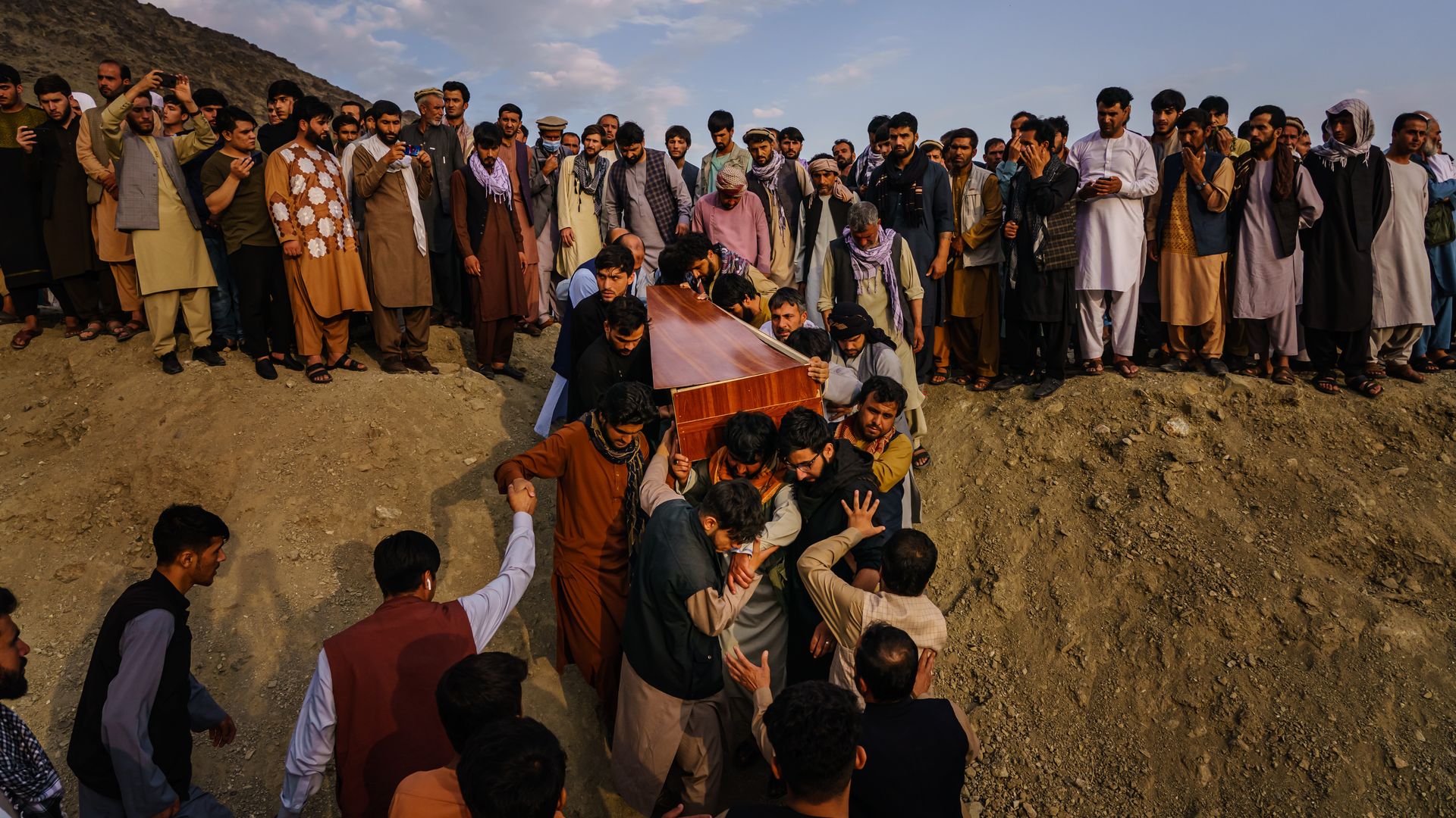 Photo of a group of Afghans carrying a casket down a hill