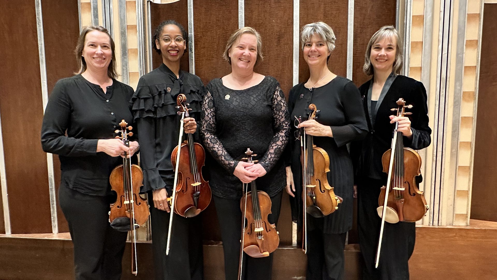 Five women with violins dressed in black. 
