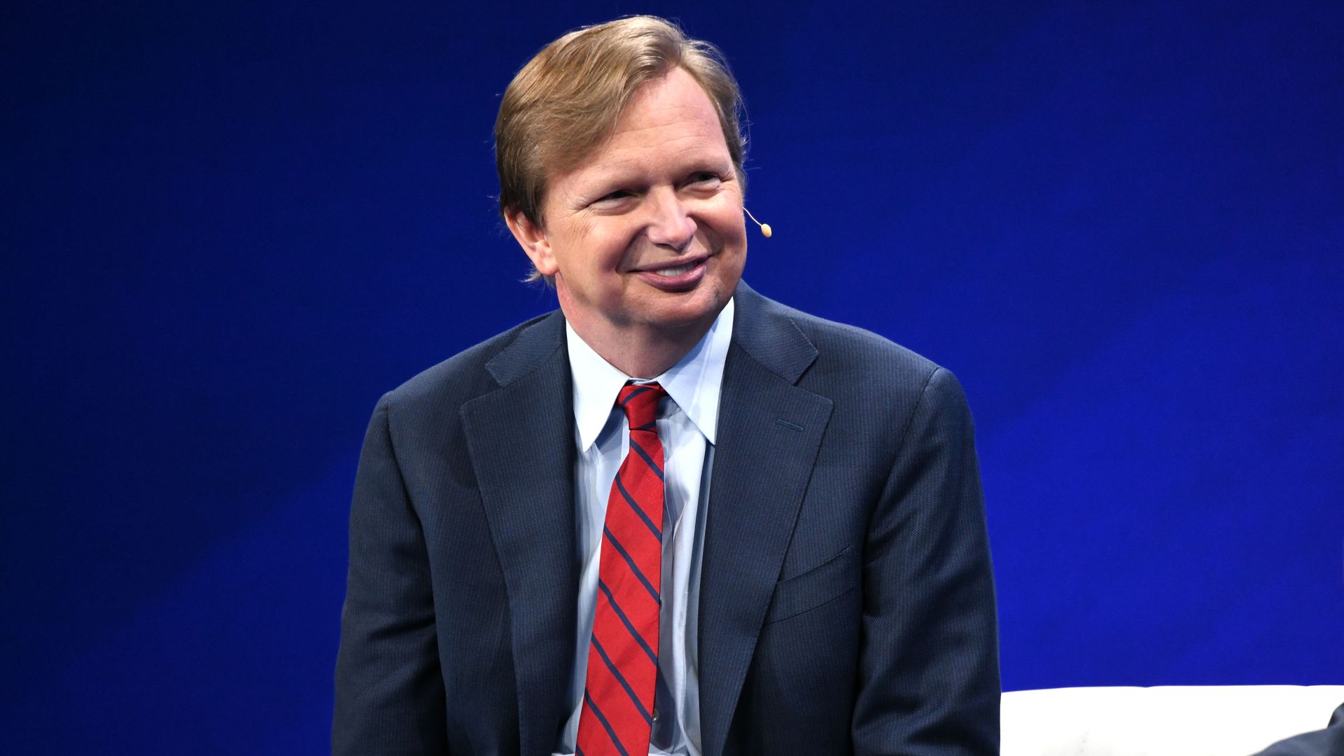 Former Obama aide Jim Messina is seen smiling while speaking on stage.