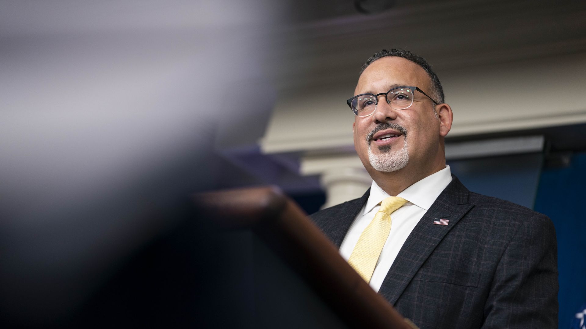 Photo of Miguel Cardona speaking from the podium