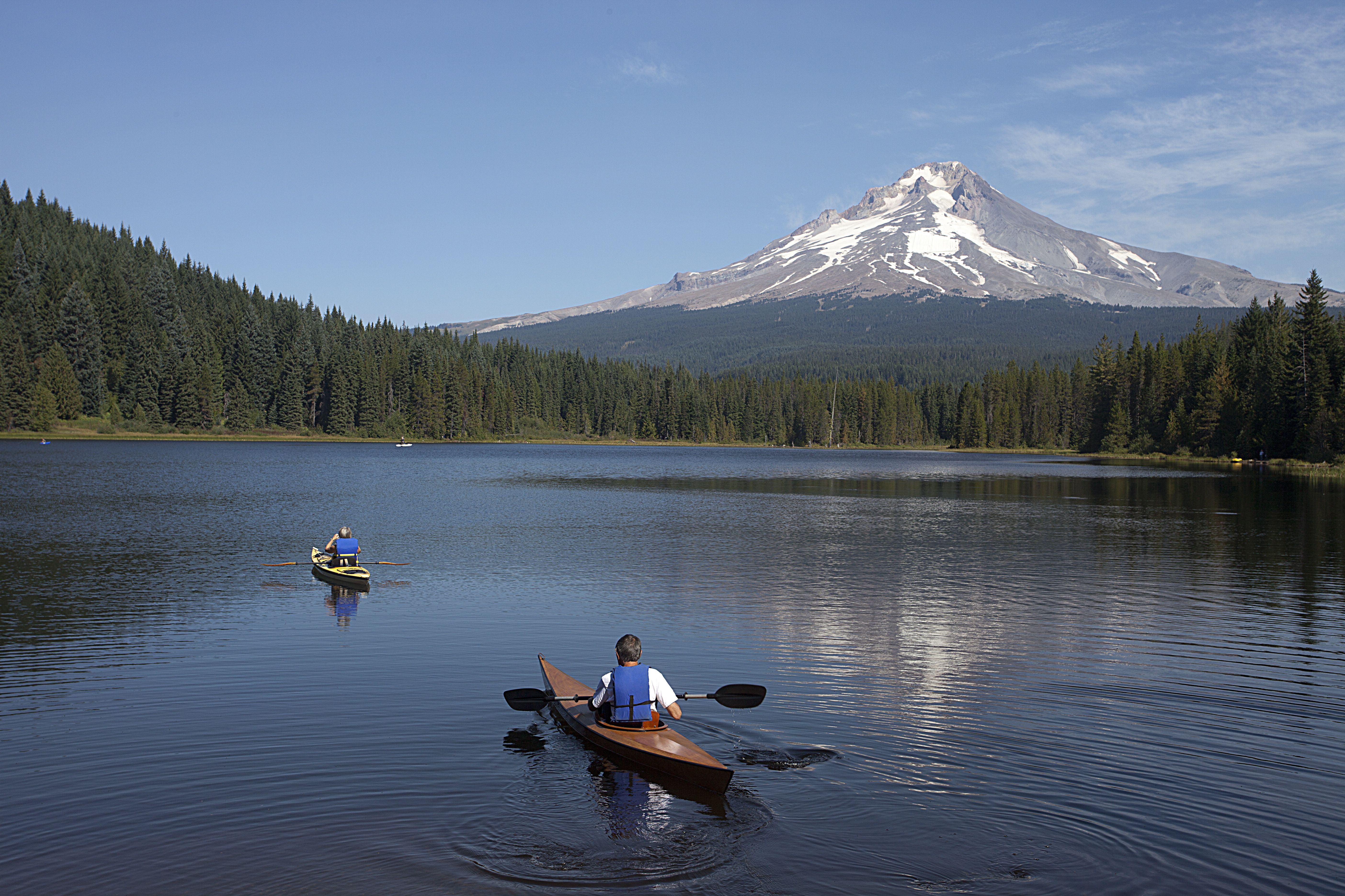 An image of two kayakers on a lake paddling with Mount Hood in the background.