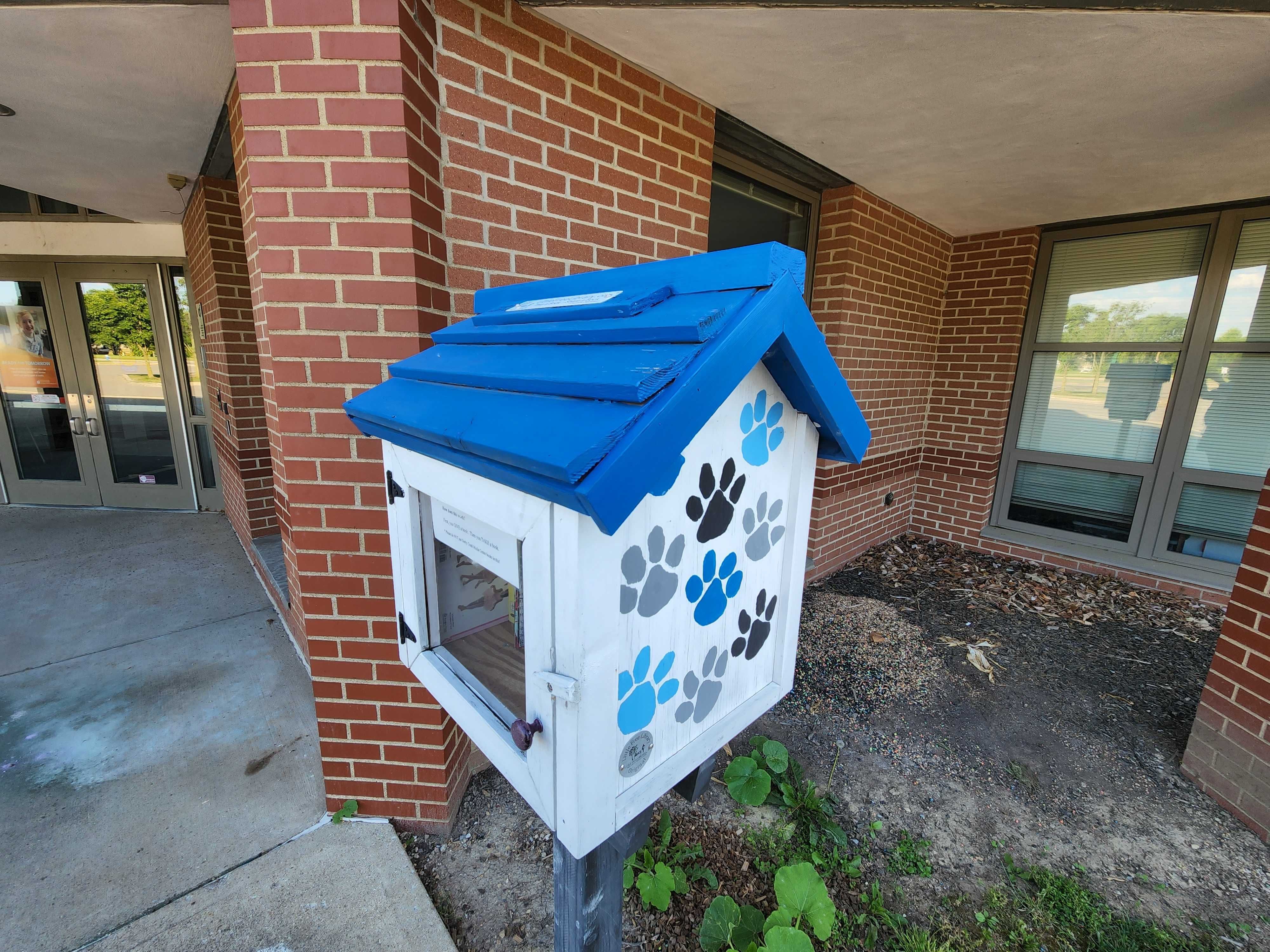A Little Free Library with paw prints painted on the side.