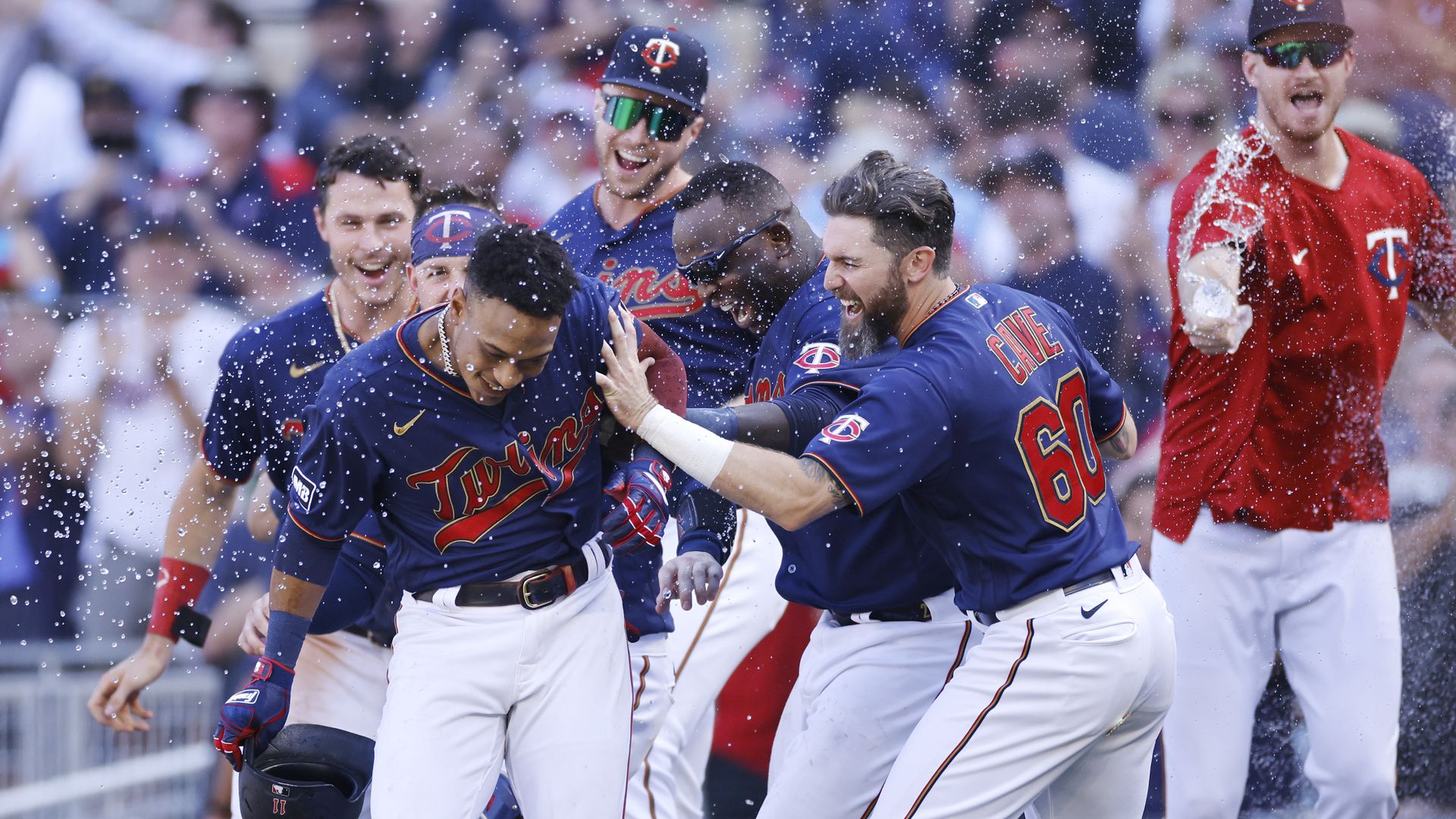 Jorge Polanco is surrounded by his teammates who are spraying water over his head on the field 