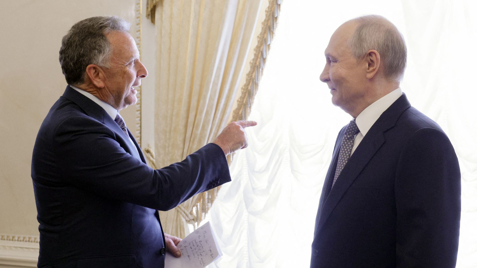 Steve Witkoff points out a window as Vladimir Putin looks at him, smiling.