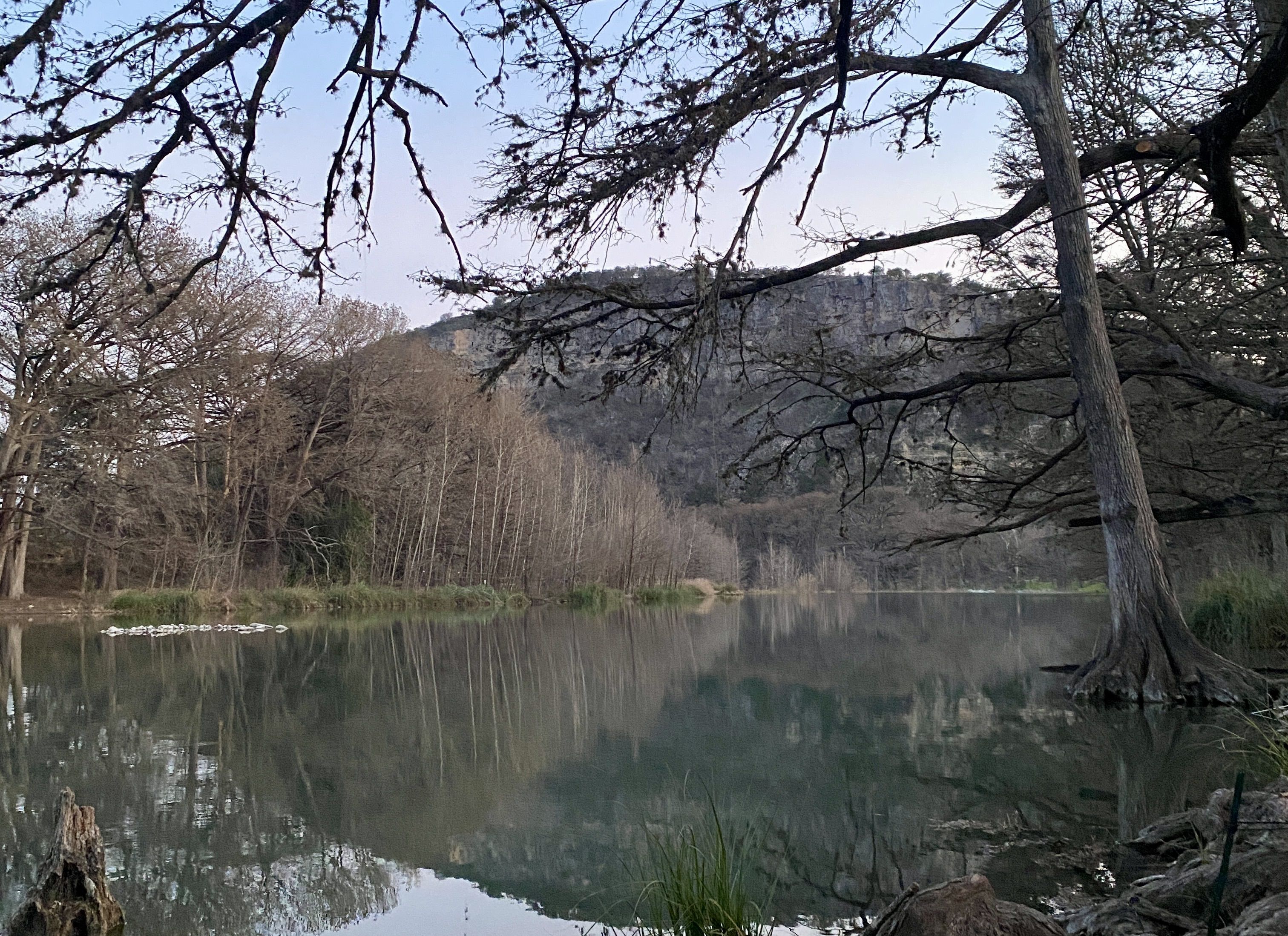 Photo of twilight hour by Frio River — with trees and a mountain. 