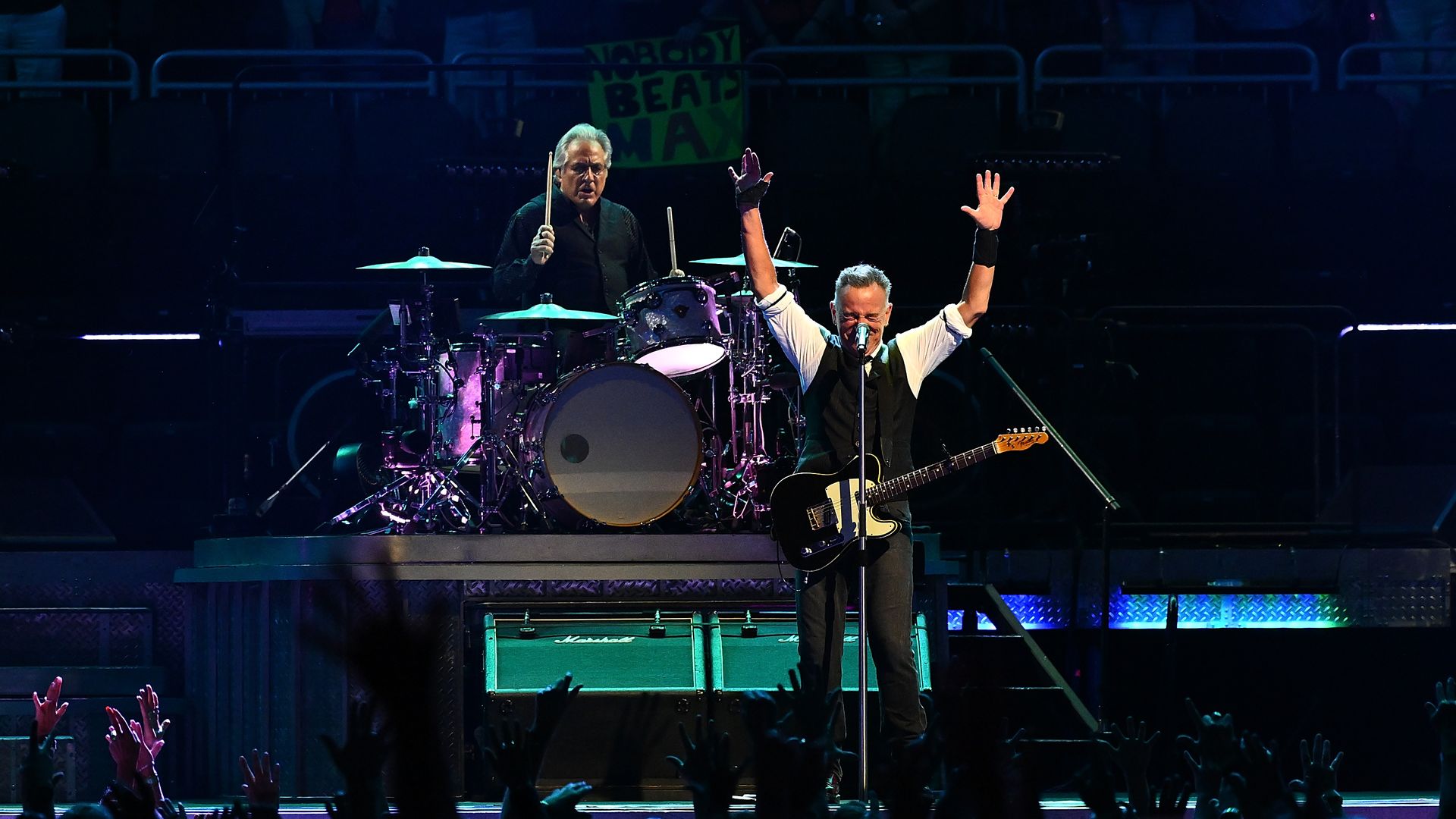 Bruce Springsteen raising his hands at a concert.