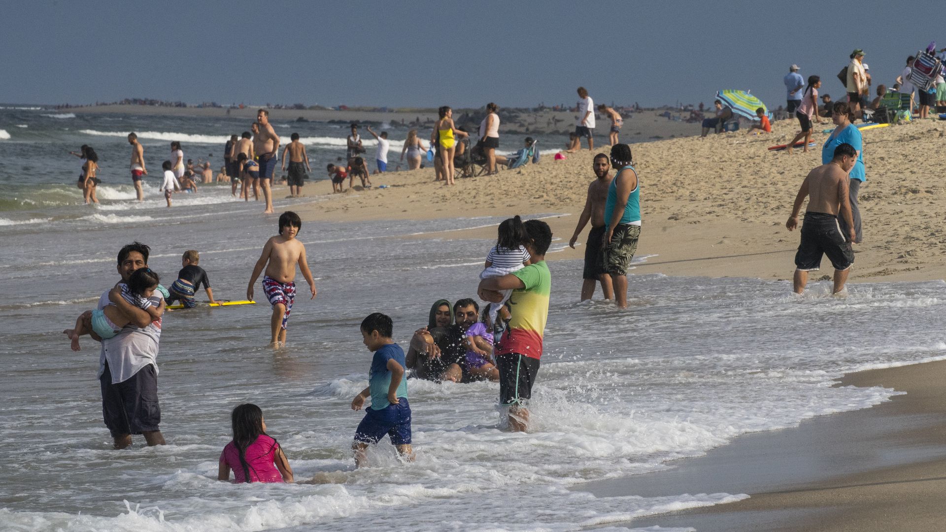 People sit in the water on a beach and play in the waves