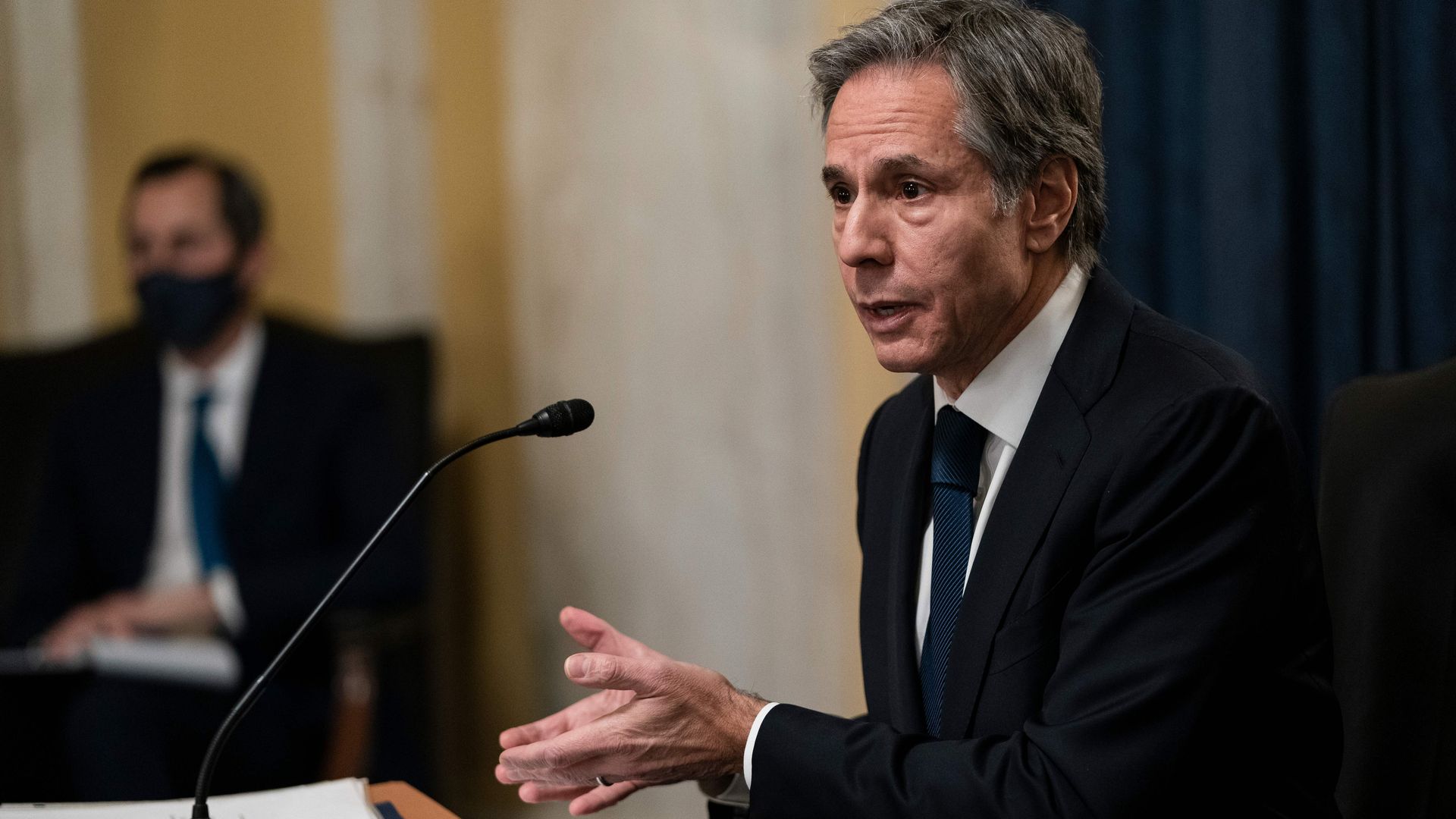 Photo of Anthony Blinken speaking into a microphone while gesturing