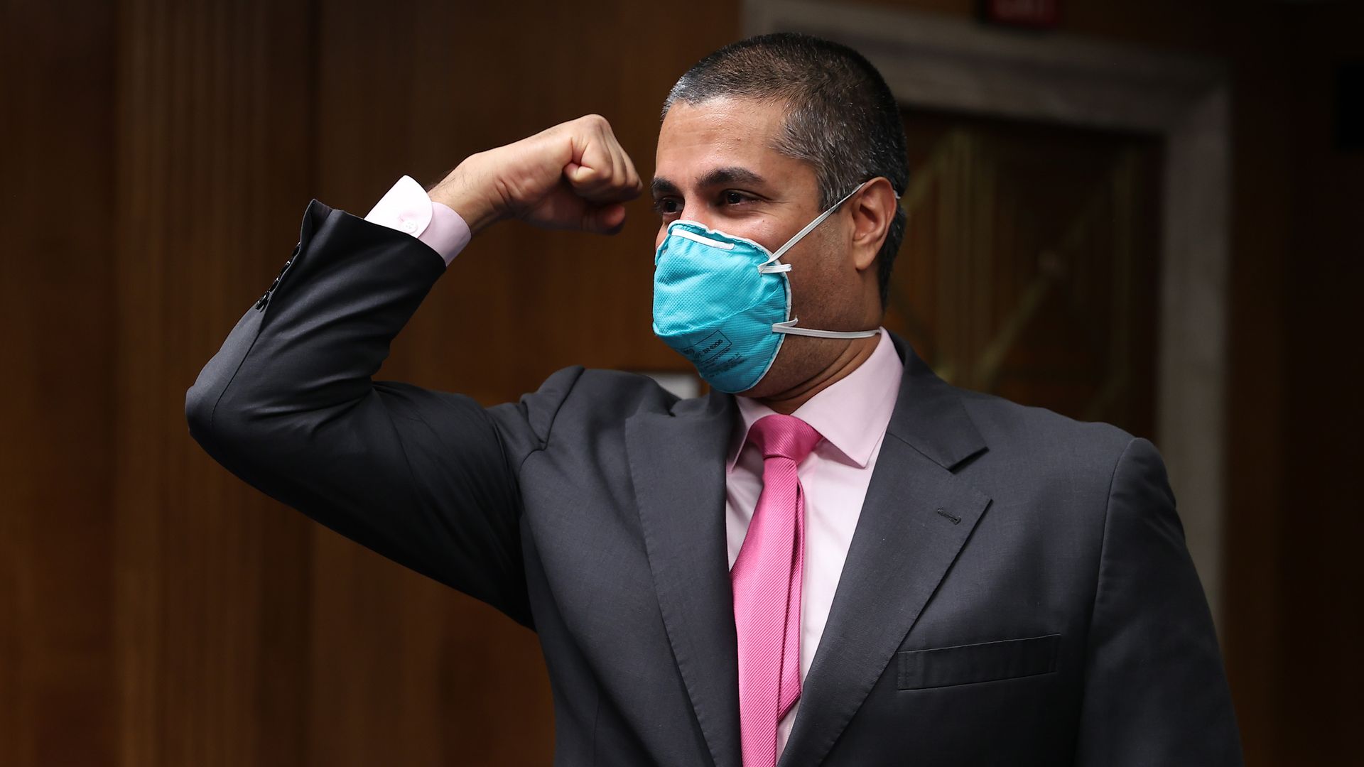 FCC Chairman Ajit Pai wears a mask and extends his elbow in greeting