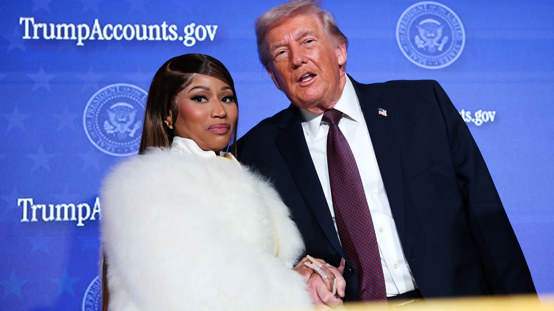 Musician Nicki Minaj (L) joins U.S. President Donald Trump on stage as he delivers remarks during the Treasury Department's Trump Accounts Summit at Andrew W. Mellon Auditorium on January 28, 2026 in Washington, DC