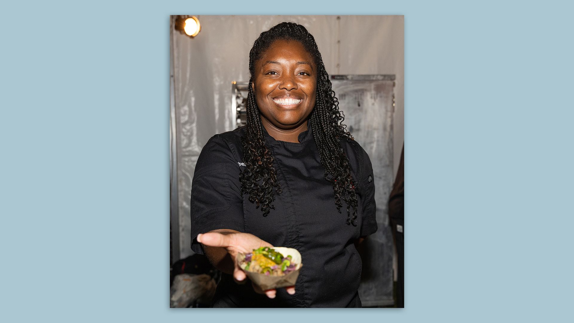 Photo of Chef Nicola Blaque holding out a taco.