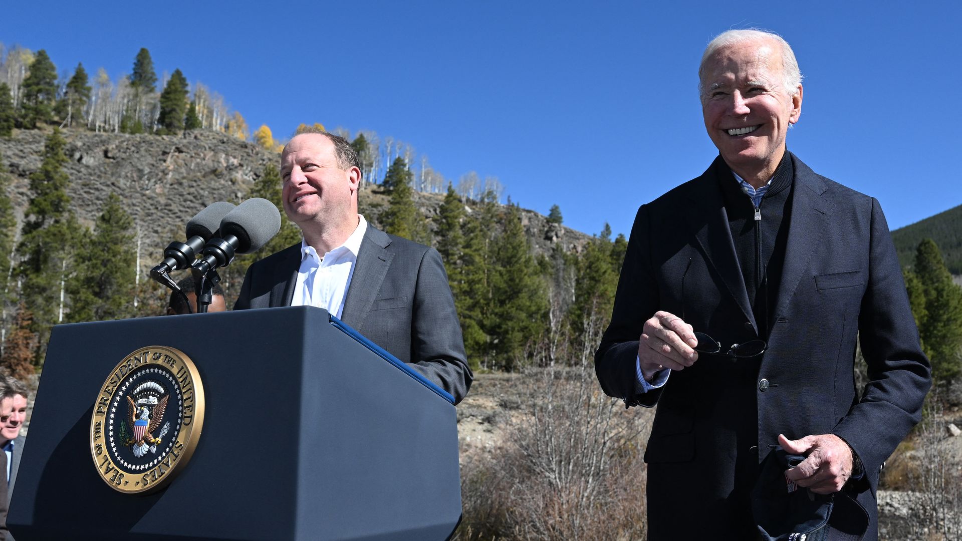 US President Joe Biden (R) smiles as Colorado Governor Jared Polis delivers remarks about protecting America's iconic outdoor spaces at Camp Hale near Leadville, Colorado, on October 12, 2022. (Photo by SAUL LOEB / AFP) (Photo by SAUL LOEB/AFP via Getty Images)