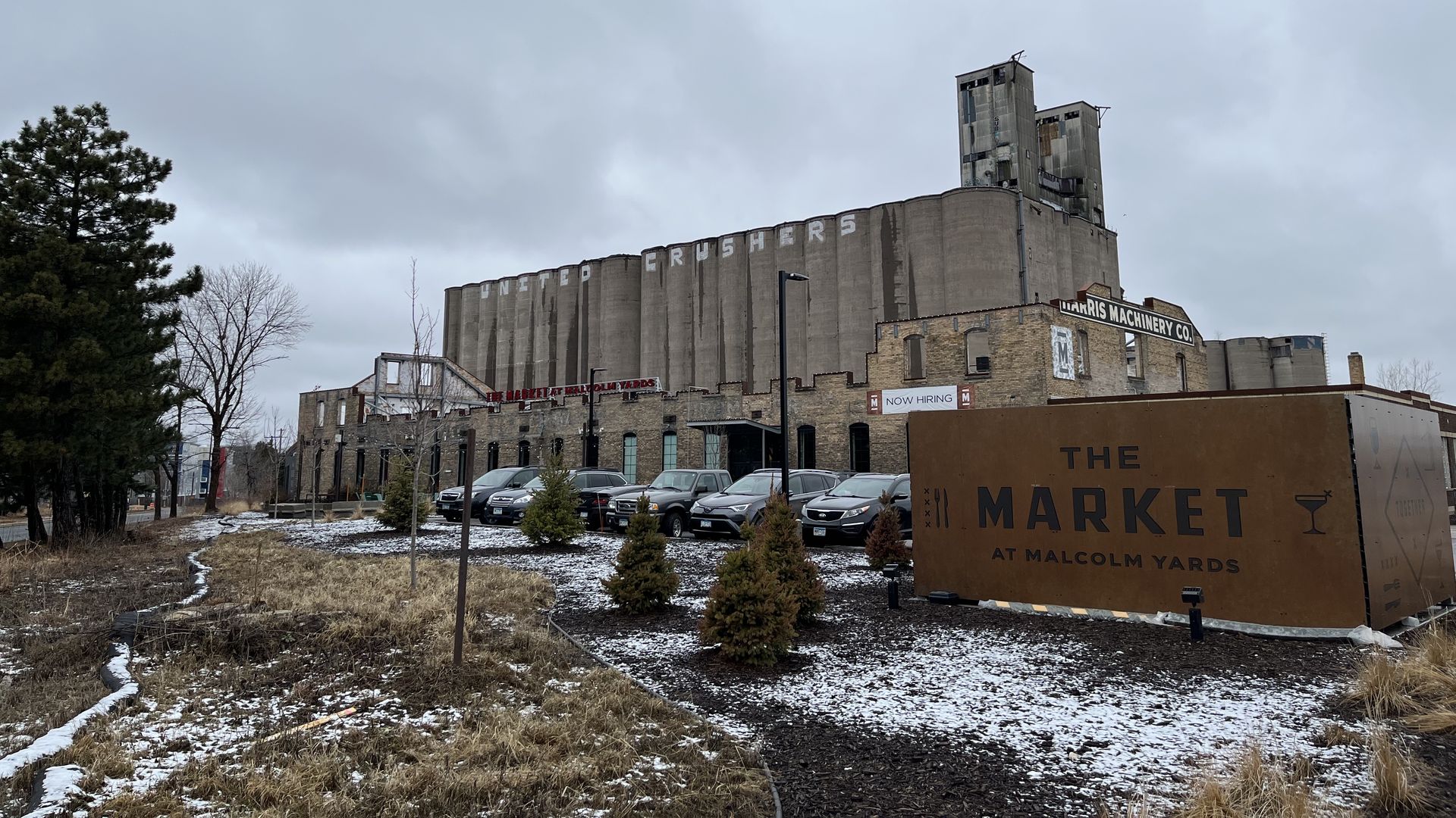 A food hall with a sign in front and silos in back 