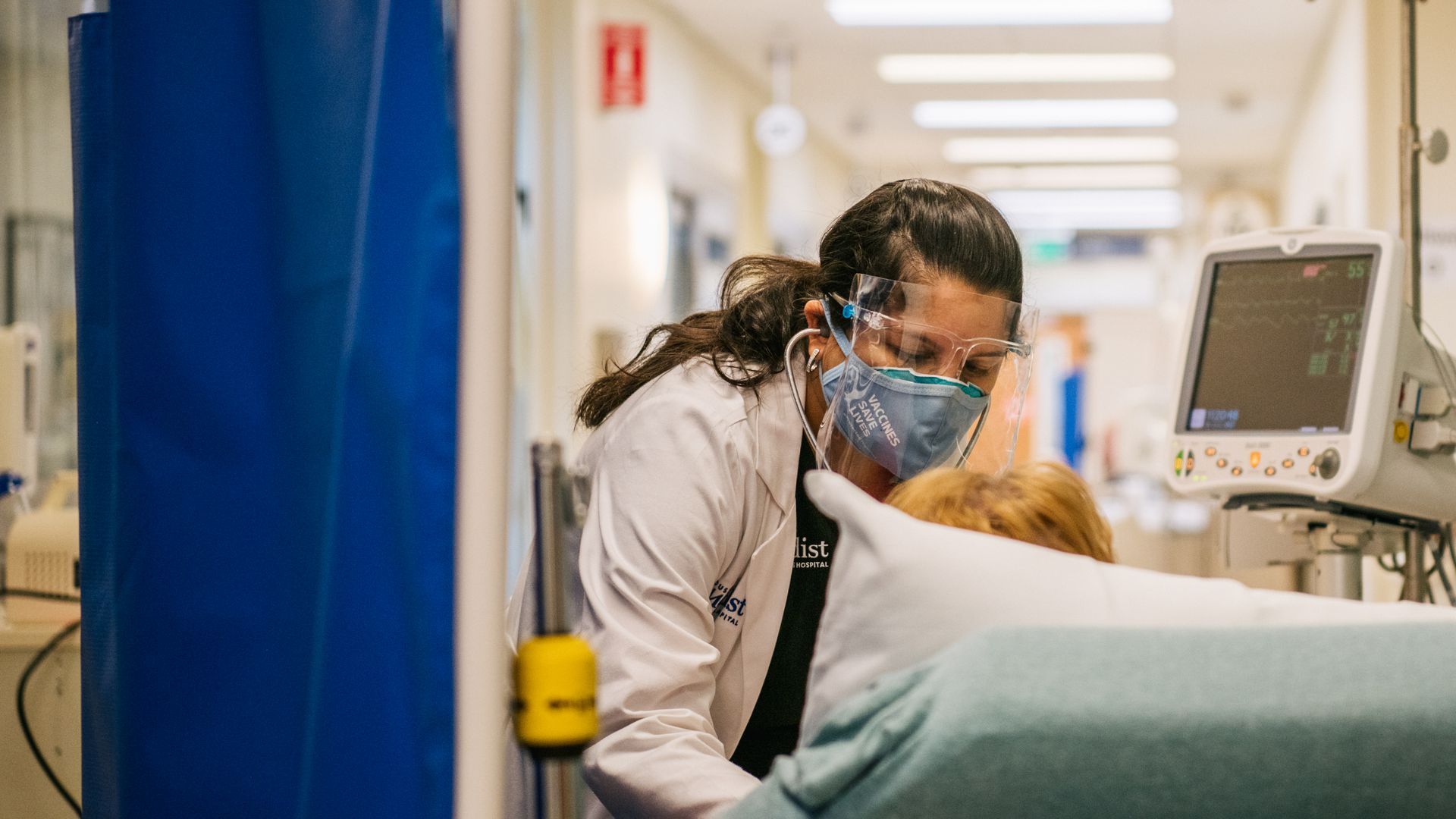 A nurse tends to a patient in a hallway 