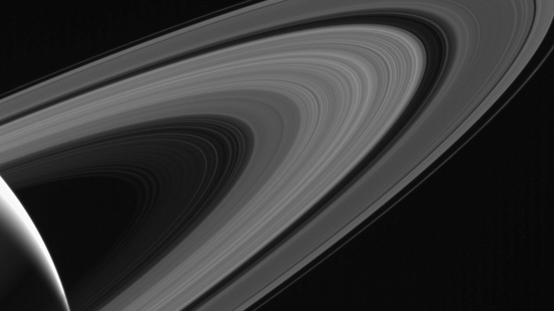 Cassini gazes across the icy rings of Saturn toward the icy moon Tethys, whose night side is illuminated by Saturnshine, or sunlight reflected by the planet