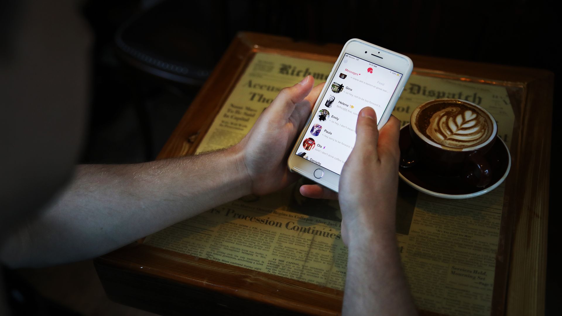 A person uses Tinder next to a cup of coffee