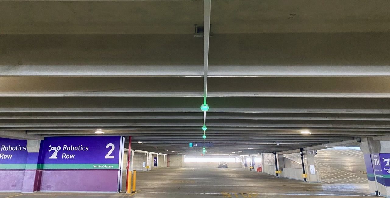 The new garage features tech with overhead sensors, real-time space counts in each row, and green lights showing available spots. 