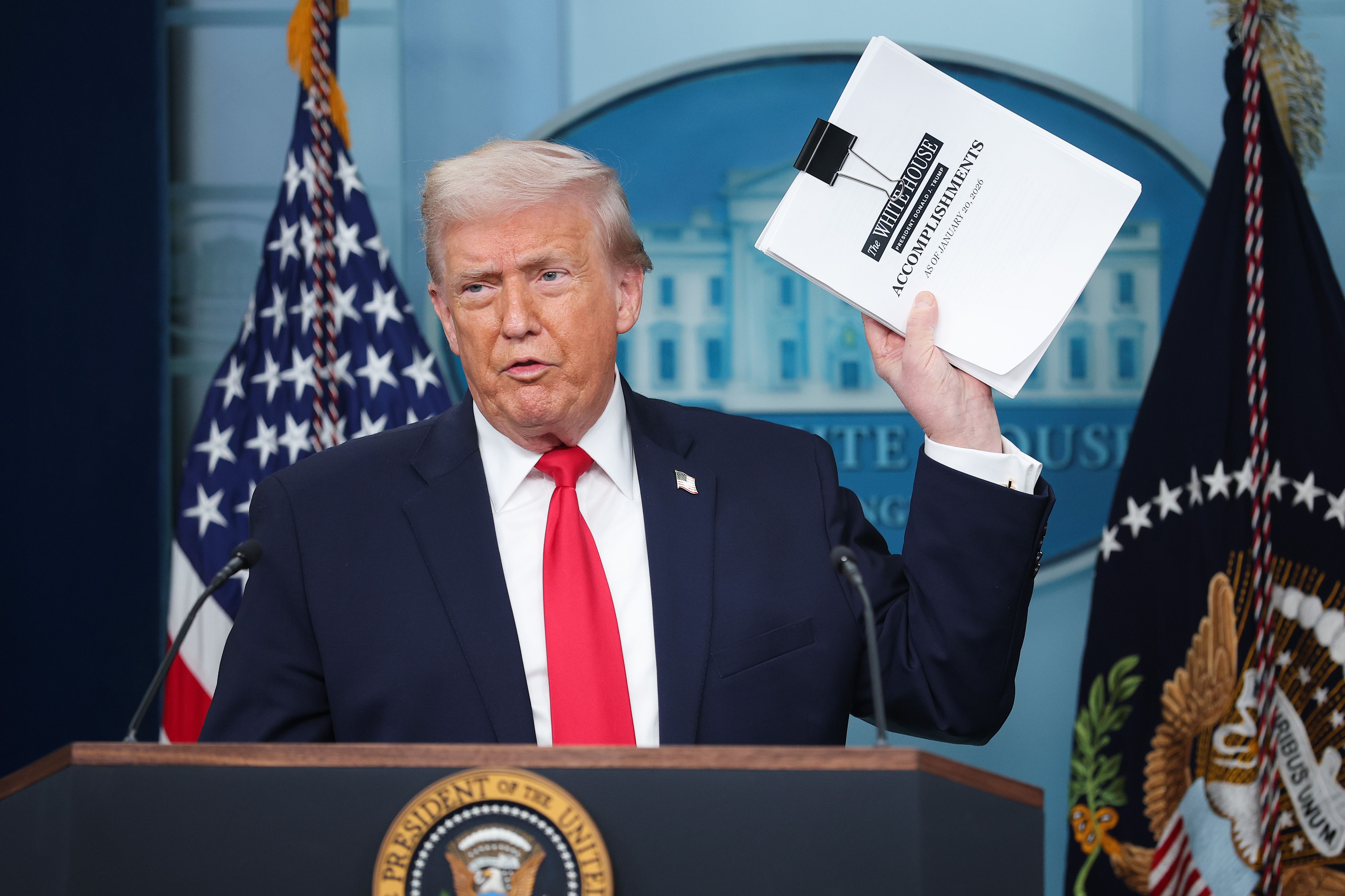  President Donald Trump displays a stack of papers labeled "The White House Accomplishments" as he arrives for a press briefing in the James S. Brady Press Briefing Room of the White House on January 20, 2026 in Washington, DC. White House Press Secretary Karoline Leavitt was joined by President Tru