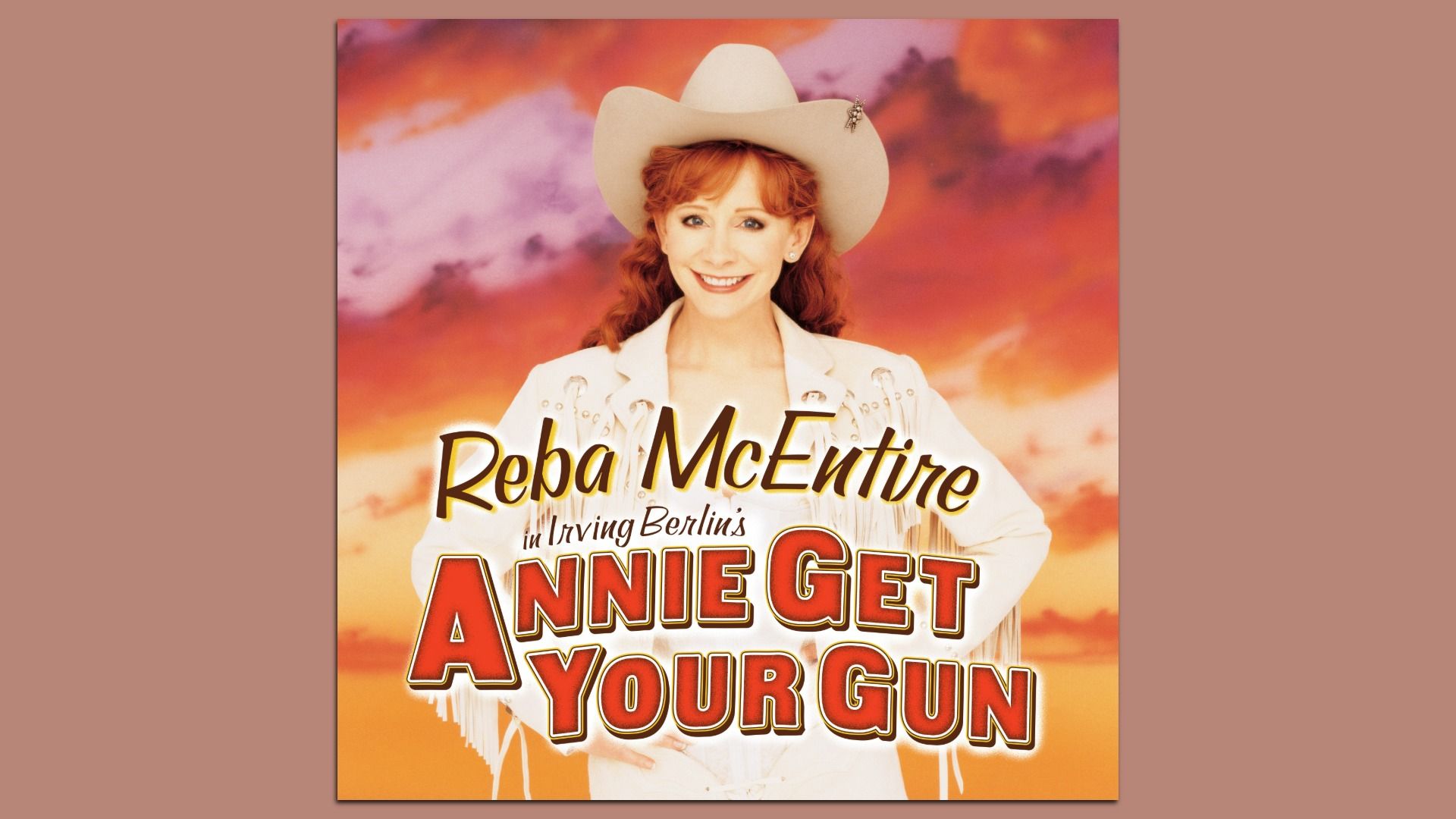Poster of Reba McEntire in a white cowboy hat and jacket, smiling against a warm orange-pink sunset. Large red title at bottom reads "Annie Get Your Gun".