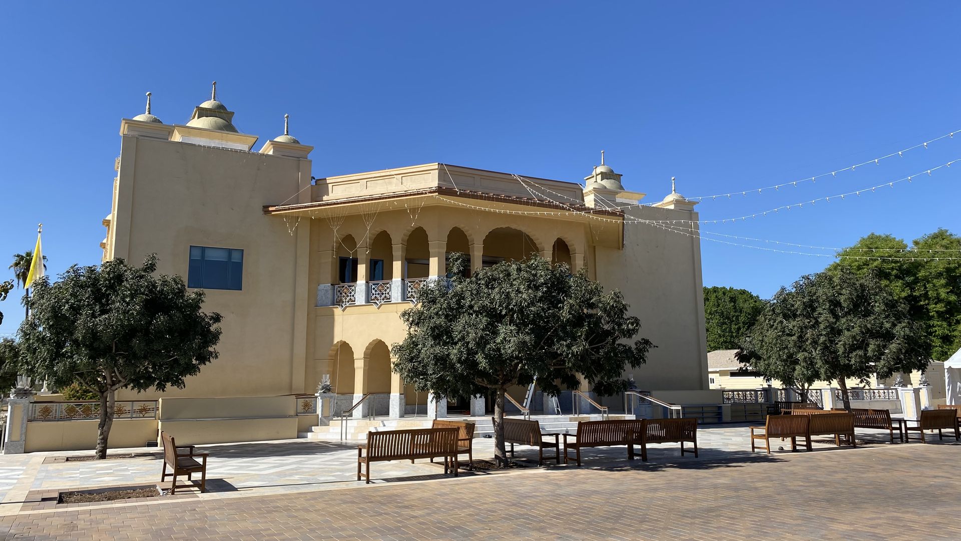 An far Eastern style temple with trees and benches in front. 