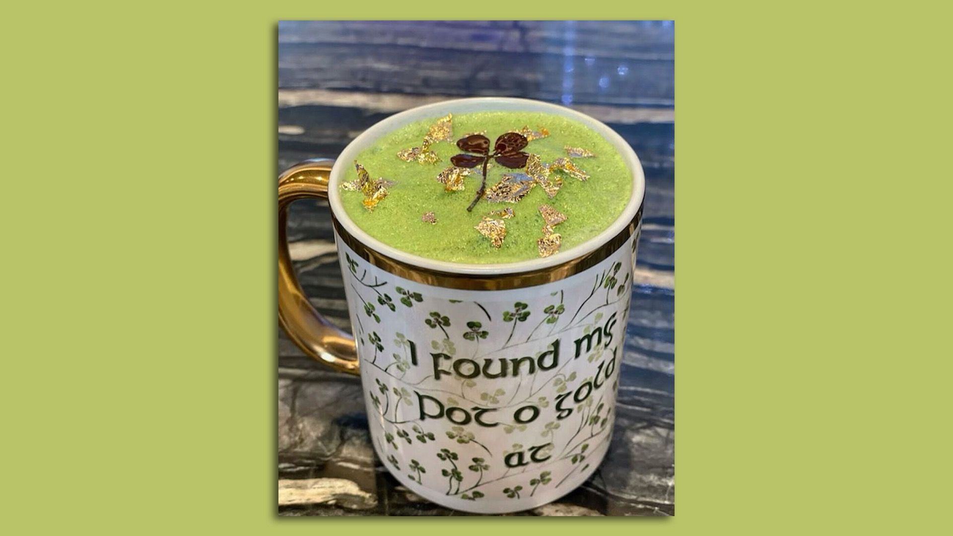 A green latte with gold leaf and a clover on top. 